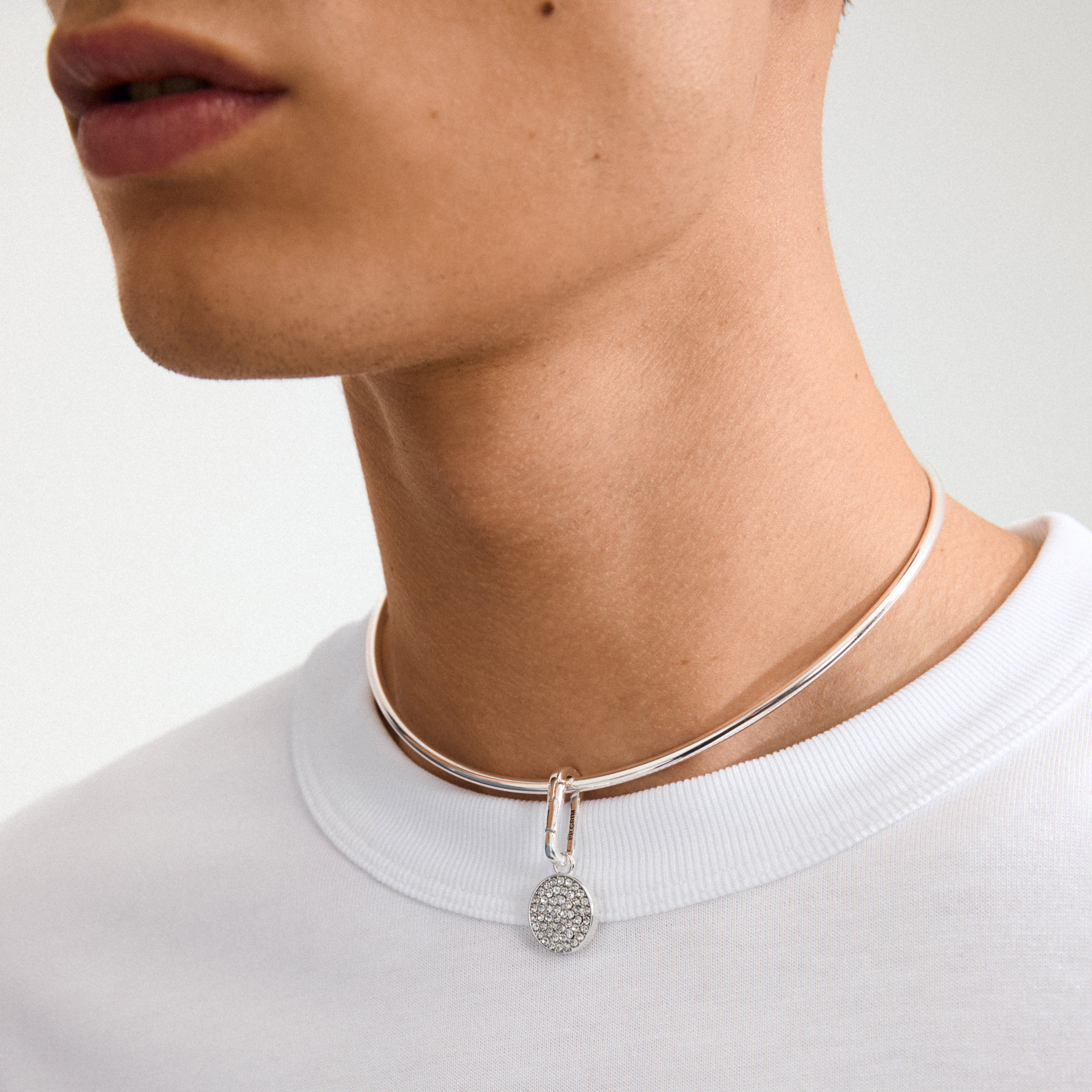 Silver-plated CHARM crystal coin pendant on a polished choker, featuring sparkling Preciosa crystals, worn with a white T-shirt for a stylish, personalized look.