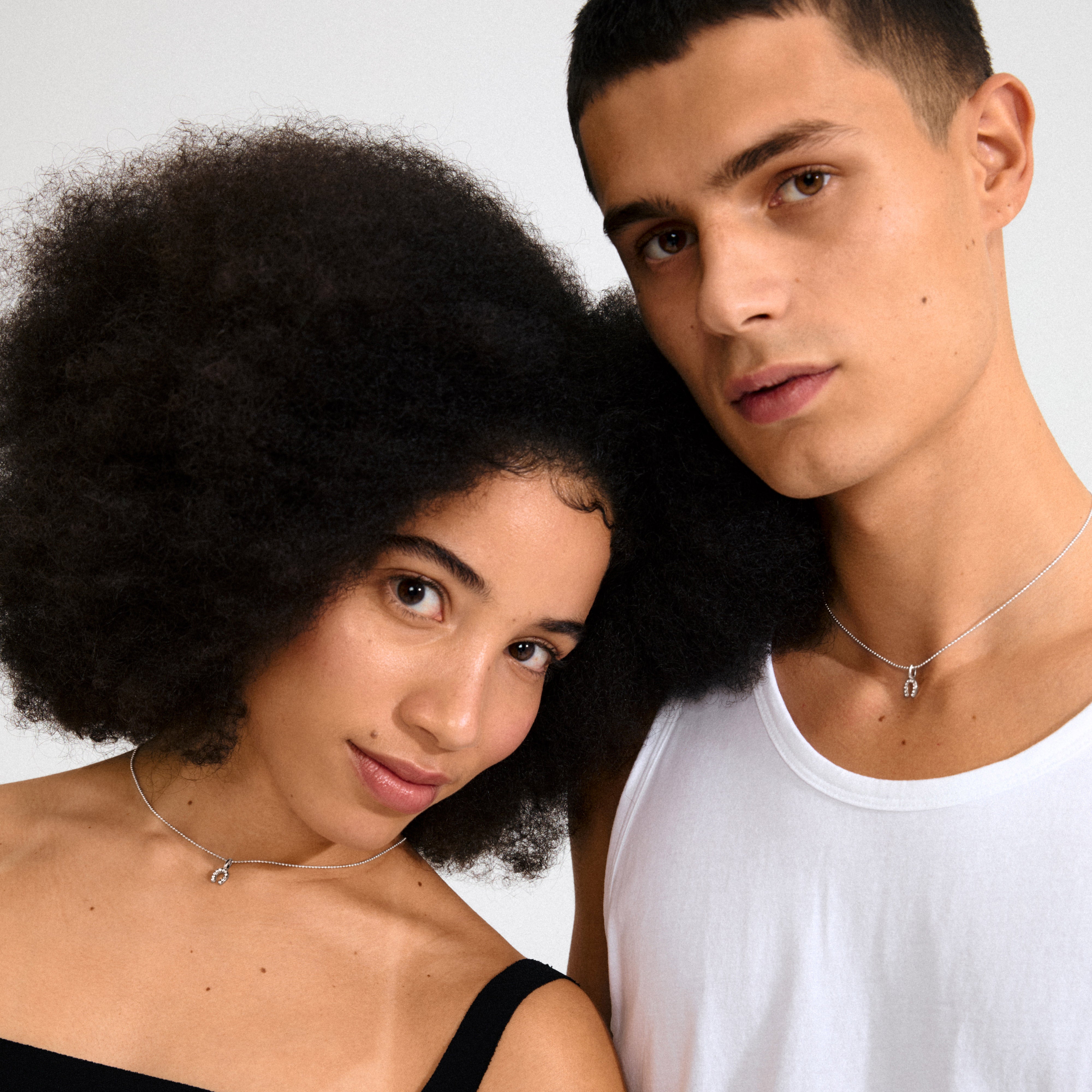 Silver-plated mini horseshoe pendant with sparkling crystals, perfect for necklaces, bracelets, or hoops, embodying personal style and good fortune. Made from 98% recycled materials.