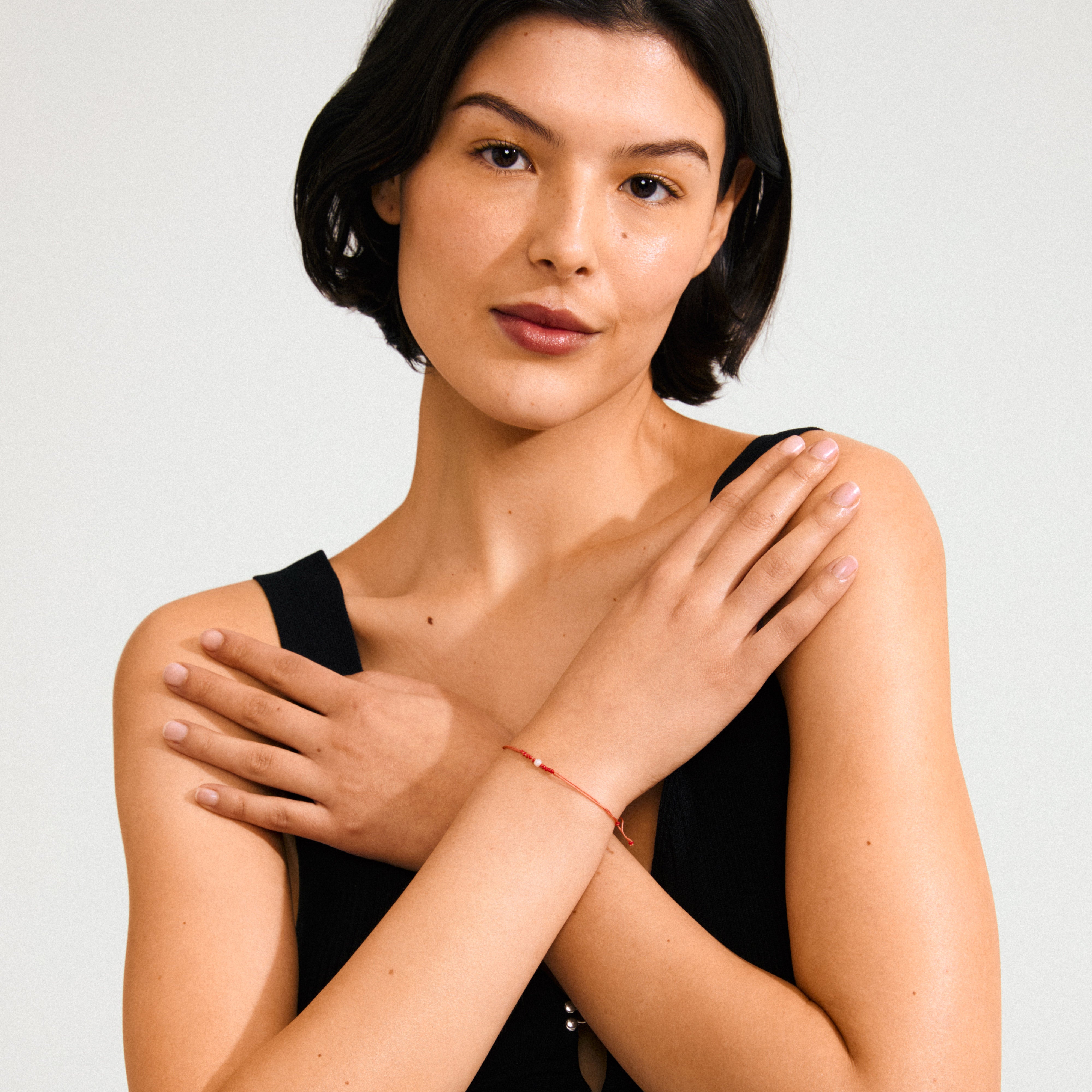 Woman wearing JUNE birthstone bracelet with red cotton cord and Moonstone, showcasing its delicate and minimalist design perfect for personal style and gifting.