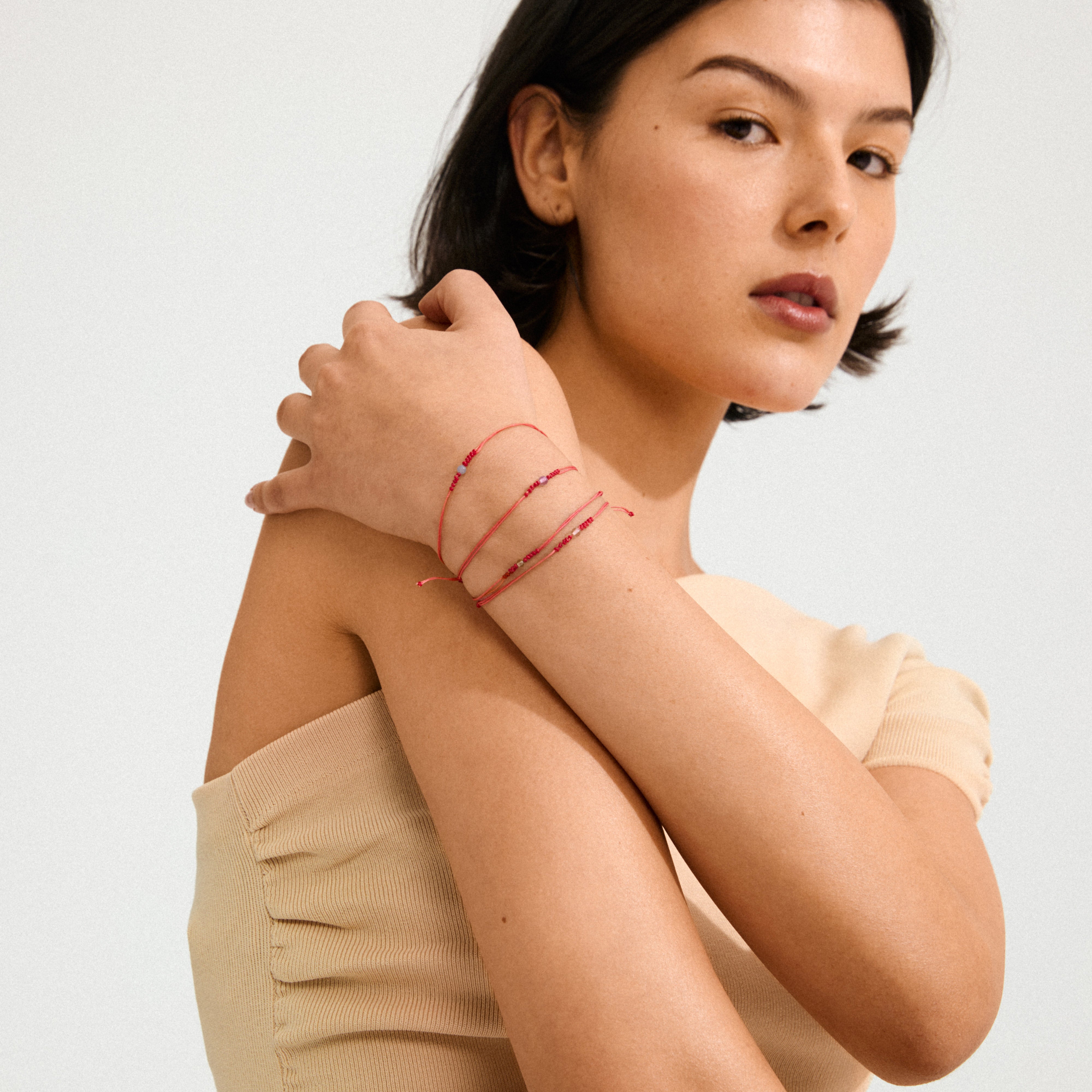 Young woman wearing JUNE birthstone bracelet, featuring red cord with Moonstone, showcasing a minimalist, boho style suitable for personal expression.
