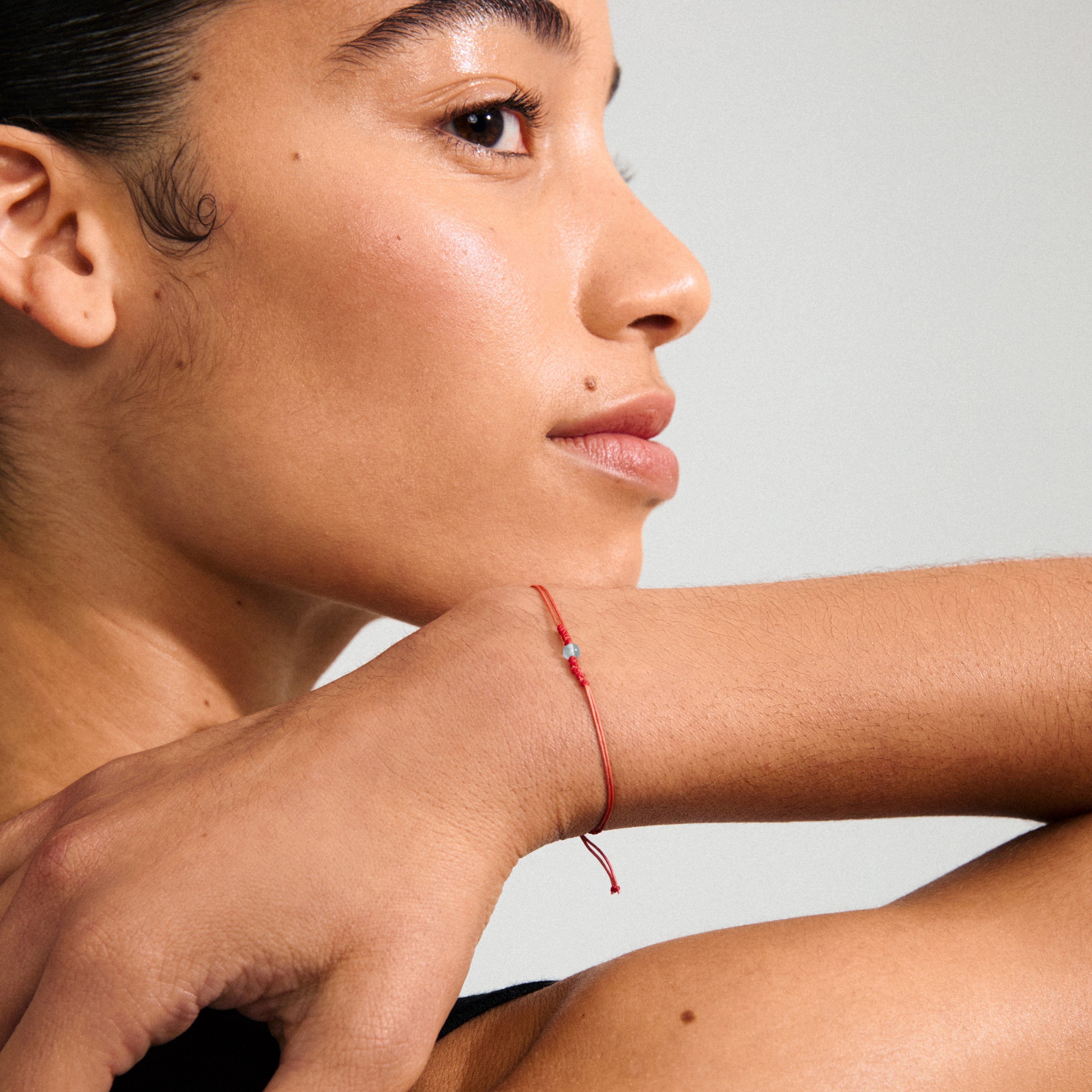 MARCH birthstone bracelet: A delicate red cotton cord bracelet featuring an Aquamarine stone, symbolizing balance and calm, perfect for a laid-back, boho style.