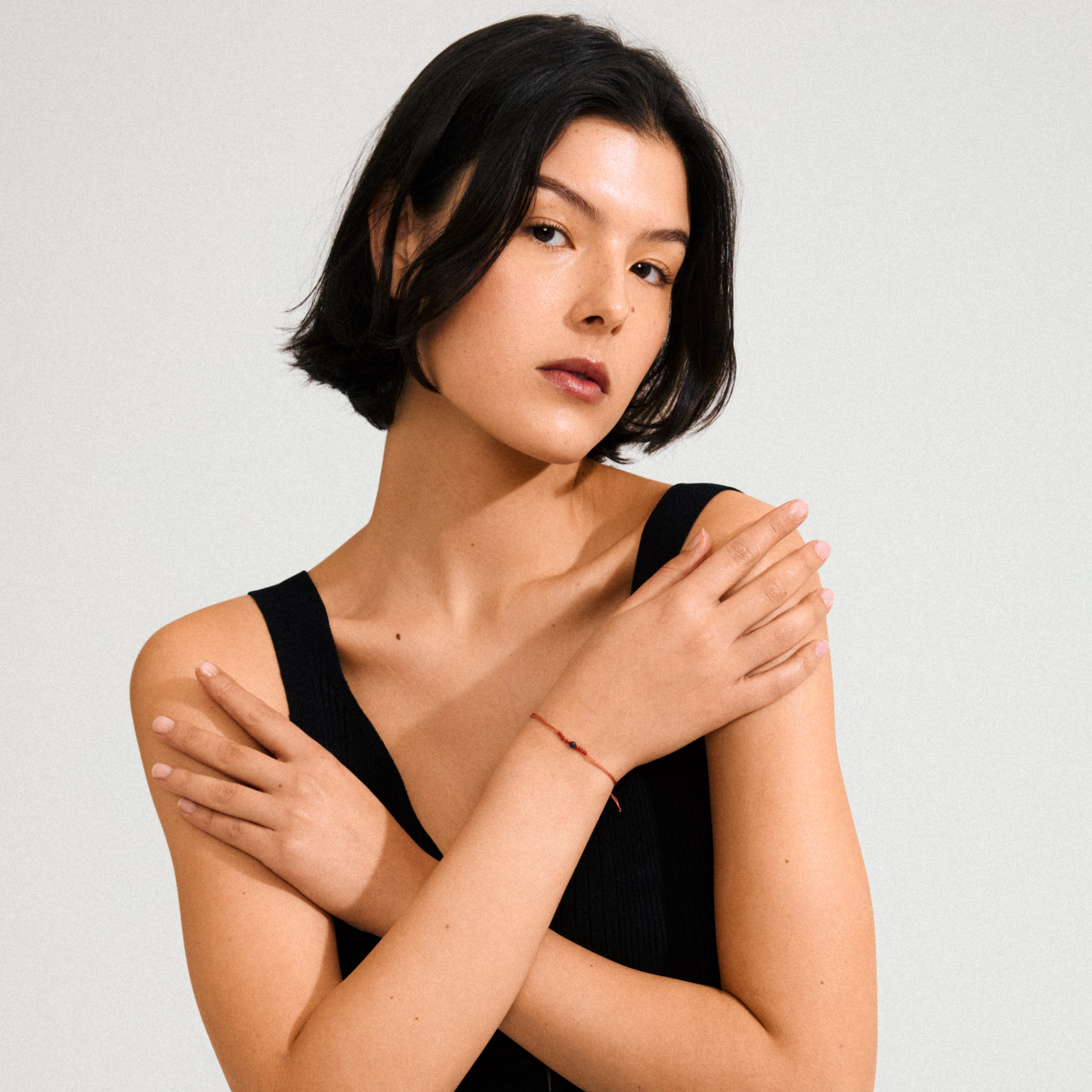 Woman wearing the SEPTEMBER birthstone bracelet, featuring a red string with a blue Lapis bead, symbolizing wisdom and strength.