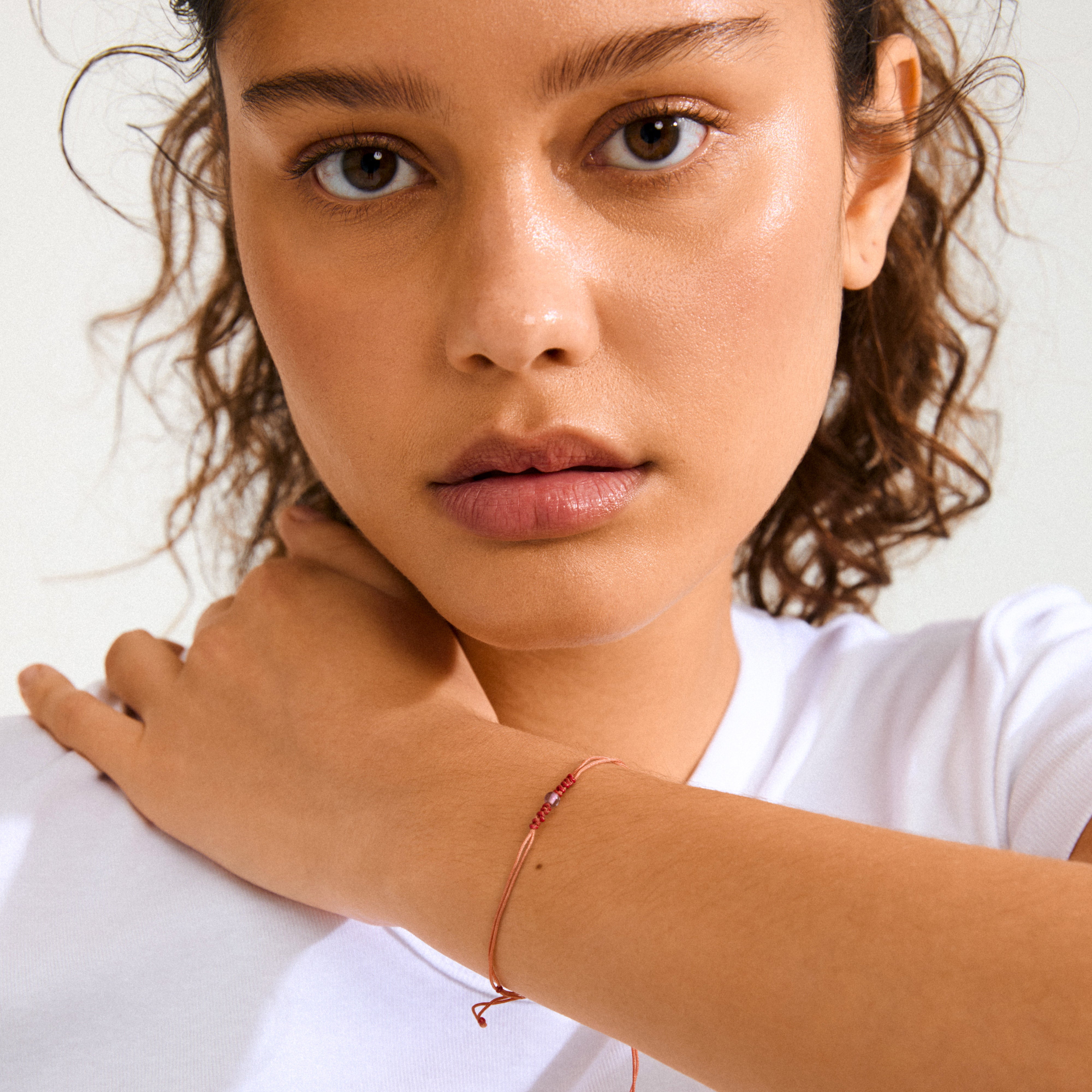 FEBRUARY birthstone bracelet on woman's wrist, featuring a red cord with adjustable closure and Amethyst, symbolizing serenity, perfect for mindful boho style.