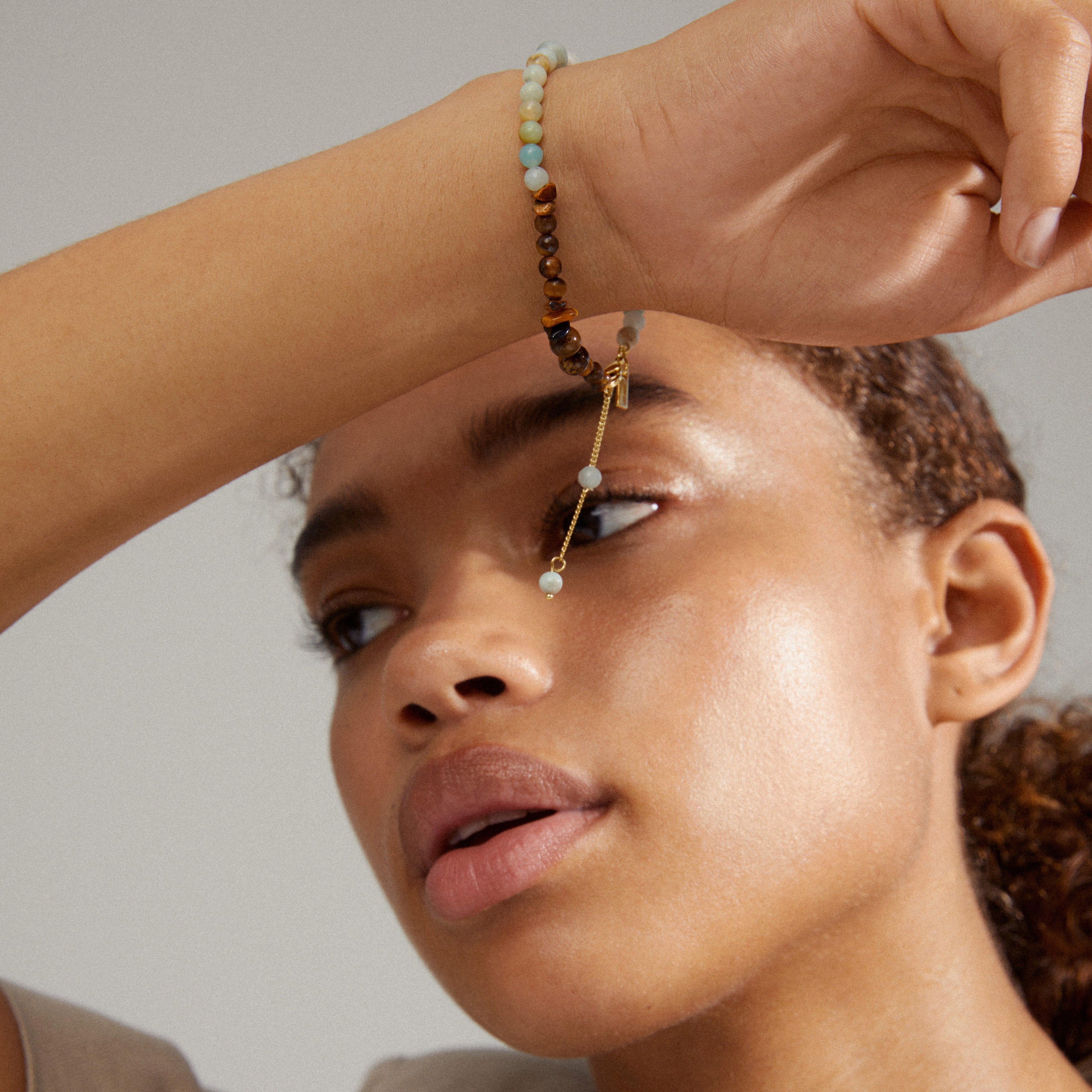 Close-up of a woman's wrist adorned with the SOULMATES bracelet mint/gold-plated, featuring contrasting amazonite and tiger eye stones, symbolizing courage and confidence.