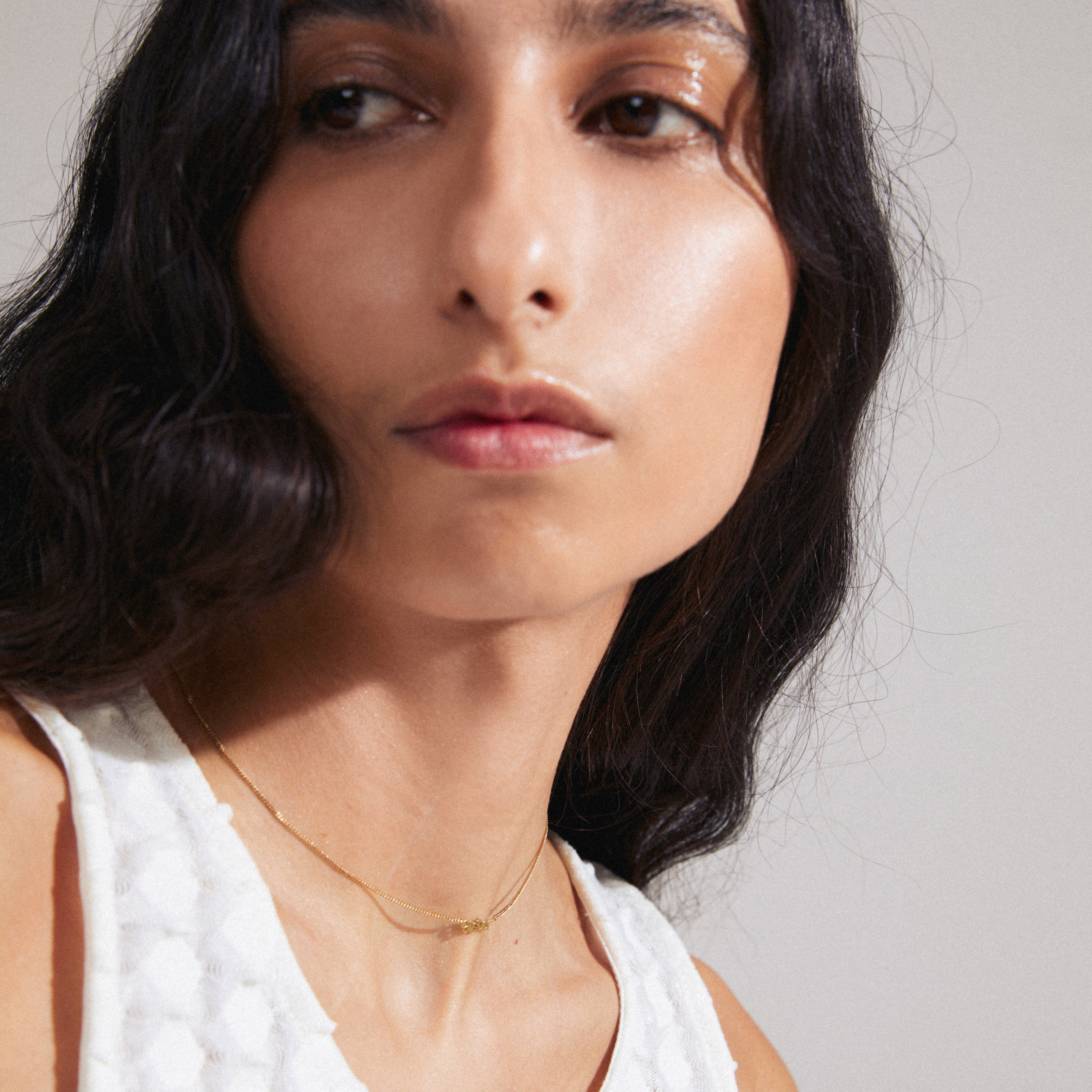 SISTER necklace gold-plated, worn by a woman with long black hair, featuring a sleek design with a cursive pendant, ideal for personalized, everyday wear.