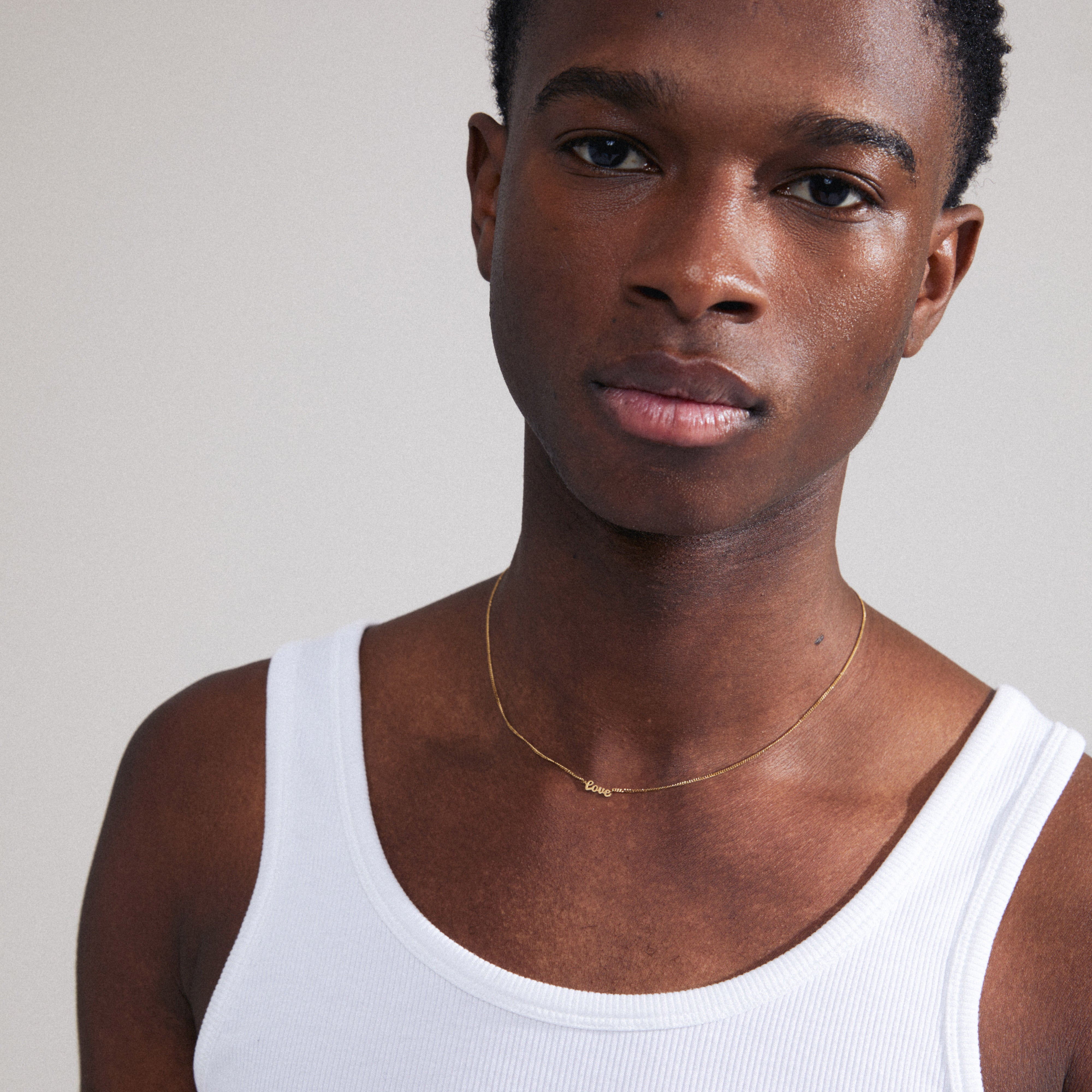 Man wearing a LOVE necklace, gold-plated with a cursive pendant, reflecting Pilgrim's inclusive and trendy style for Gen Y & Z.