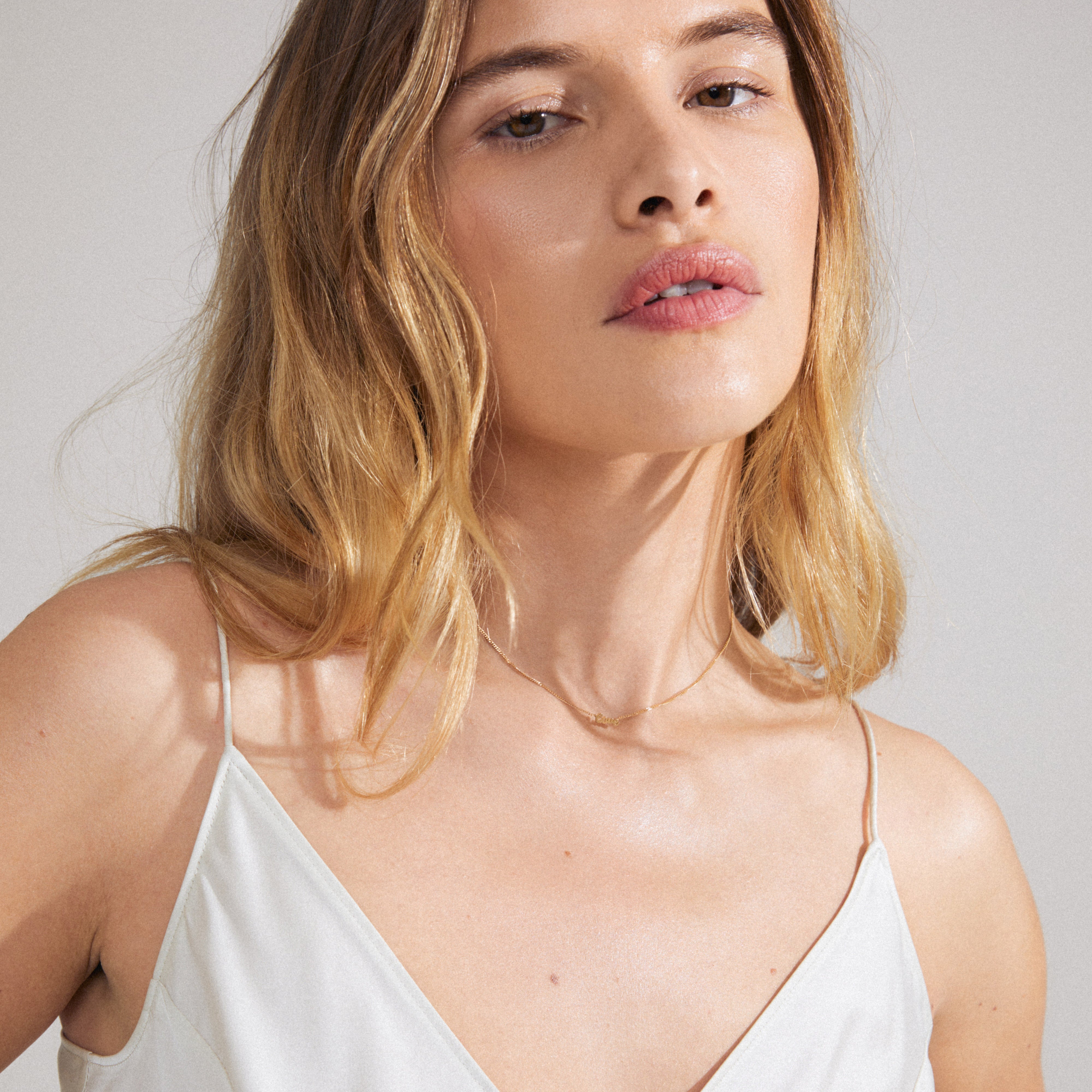 LOVE necklace gold-plated on woman's neck, featuring a sleek design with 'LOVE' pendant, embodying Scandinavian quality and style. Perfect for personal styling or gifting.