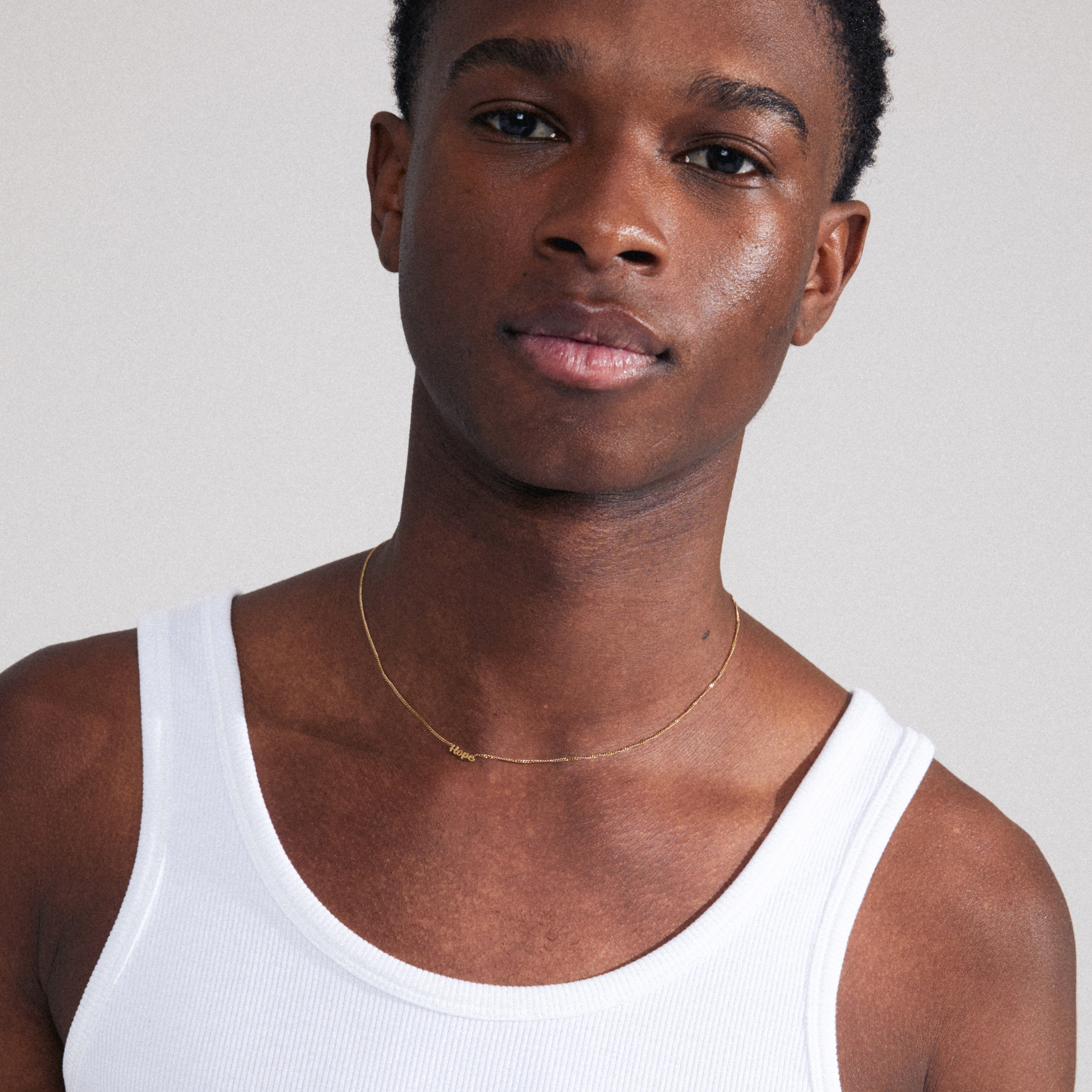 Gold-plated HOPE necklace shown on a man wearing a white tank top; features a cursive script pendant. Ideal for personal styling or gifting.