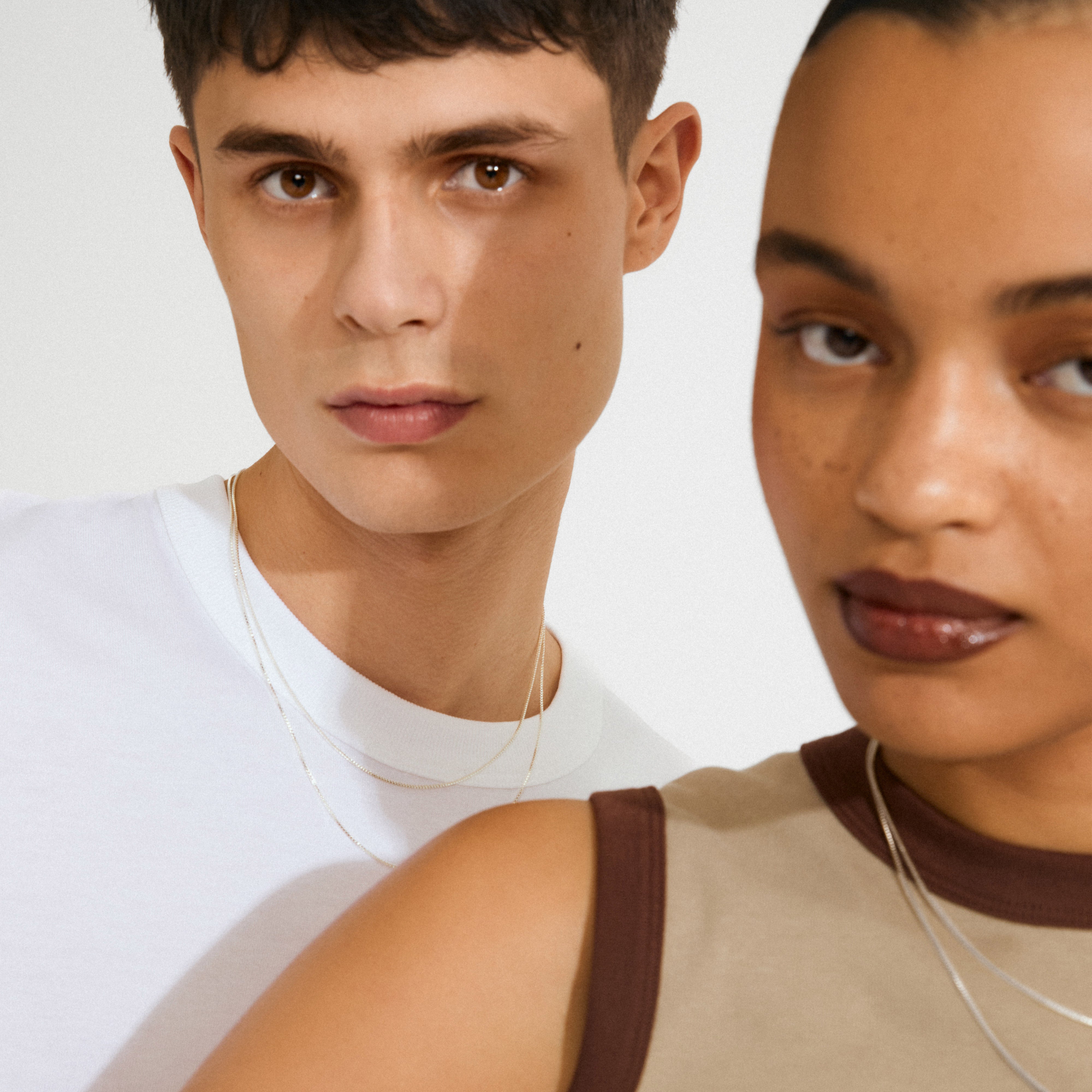 Two young adults showcasing the Lock with 2 lobsters, silver-plated clasp, elegantly layering necklaces for a trendy, tangle-free look in line with Pilgrim's Scandinavian style.