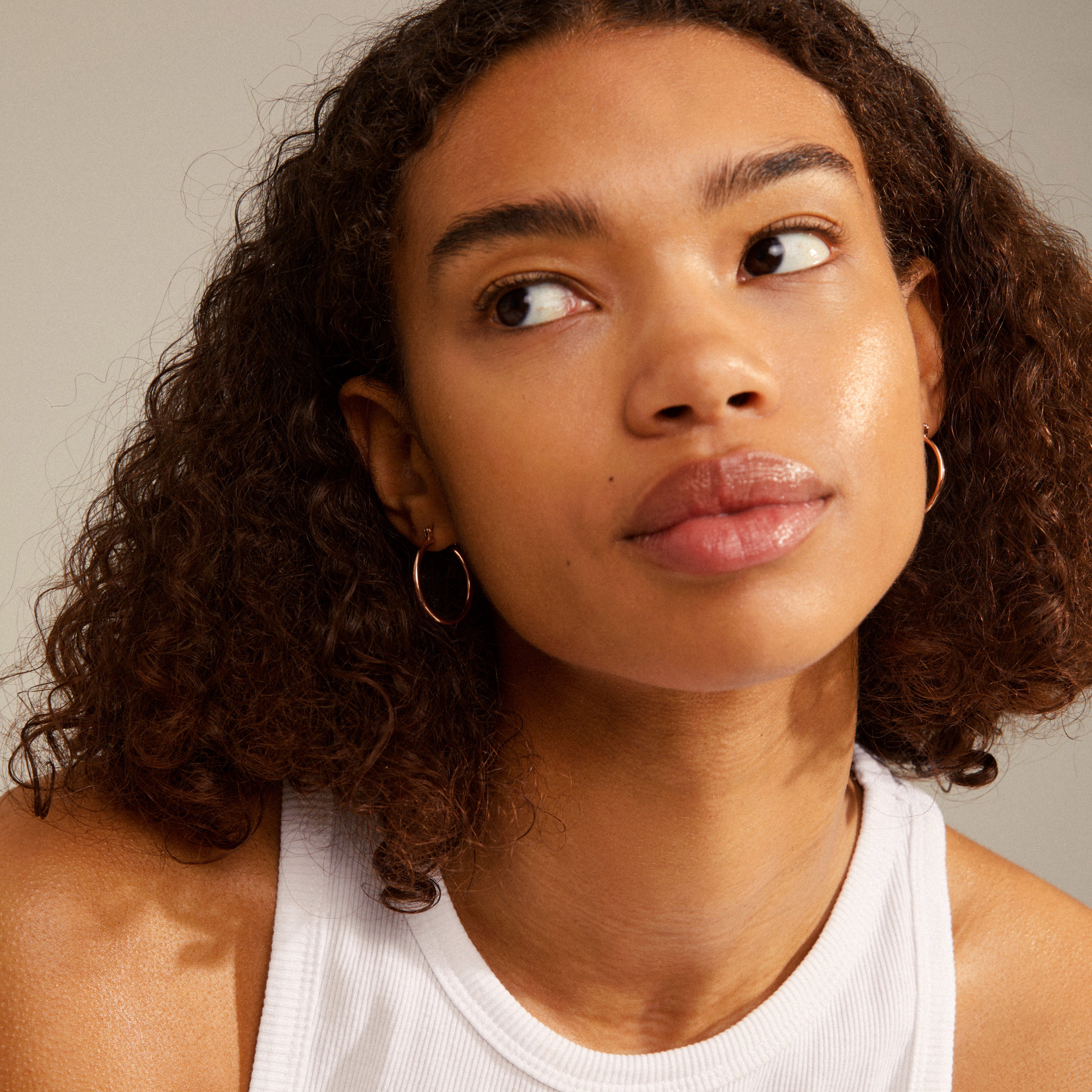 LAYLA medium hoop earrings rosegold-plated, worn by a woman looking up, showcasing the elegant creoles' design with a user-friendly click clasp.