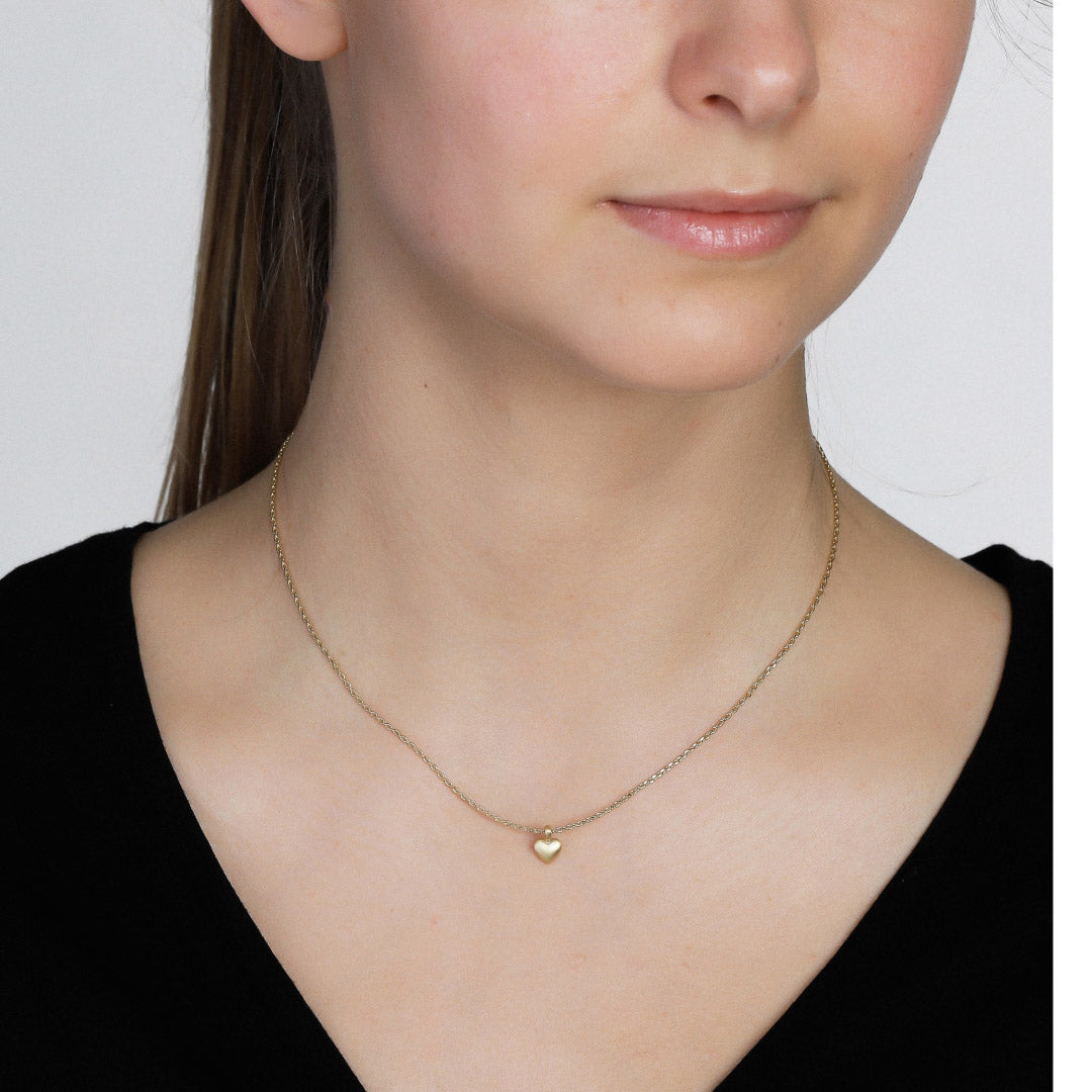 SOPHIA tiny heart pendant necklace, gold-plated, worn by a woman; features a satin-matt finish, highlighting its delicate, romantic design.