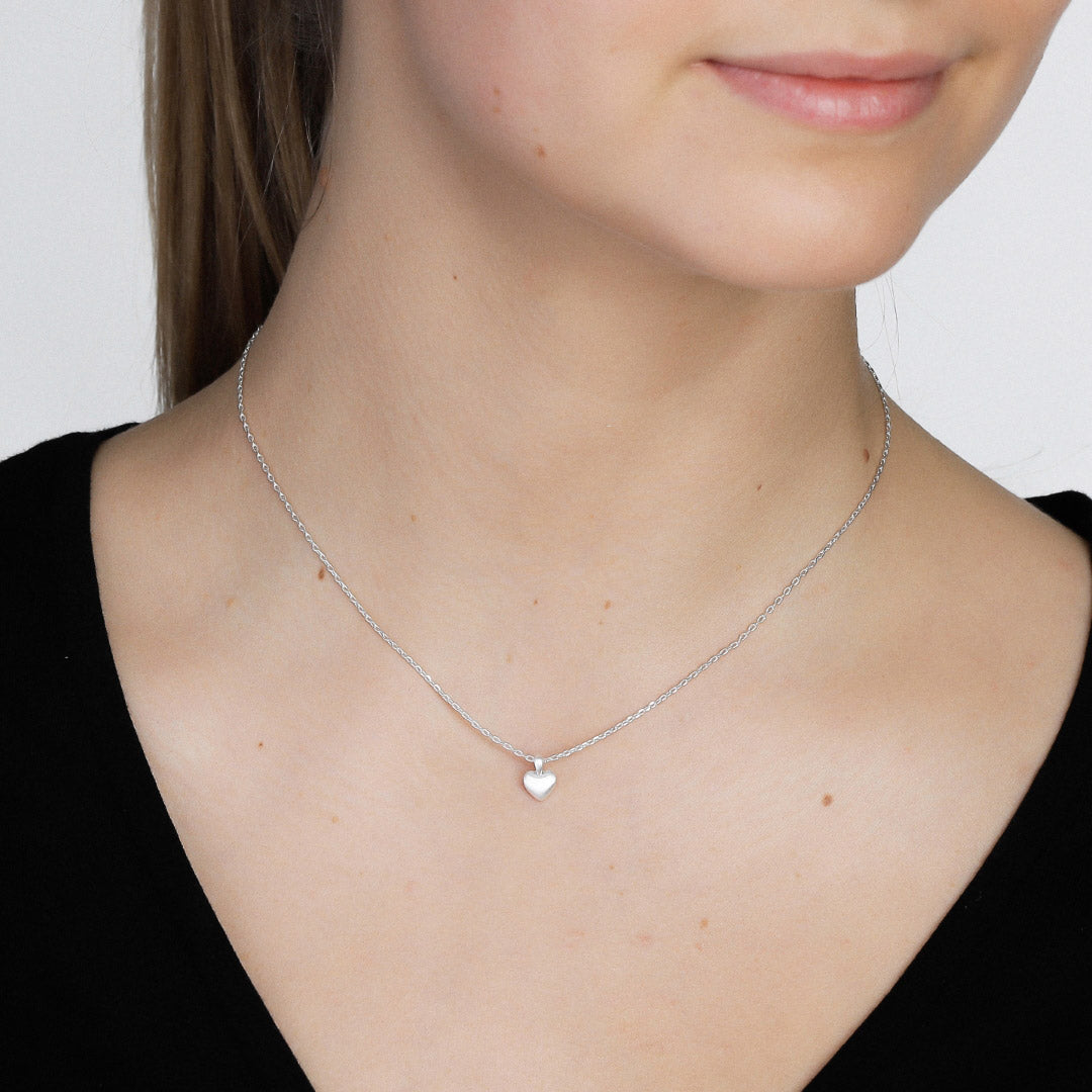 Sophia tiny heart pendant necklace, silver-plated, adorning a woman's neck. A delicate, stylish piece perfect for layering or wearing solo.