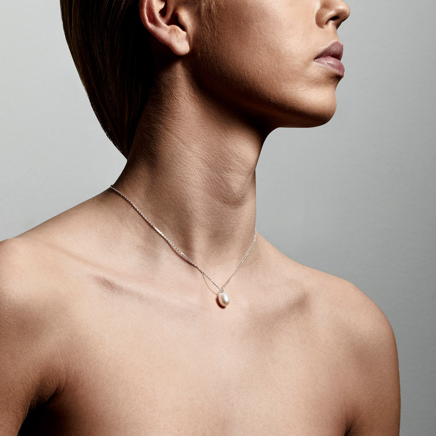 EILA freshwater pearl necklace silver-plated, featuring a droplet-shaped pearl pendant, elegantly worn by a woman, showcasing its modern and timeless design.