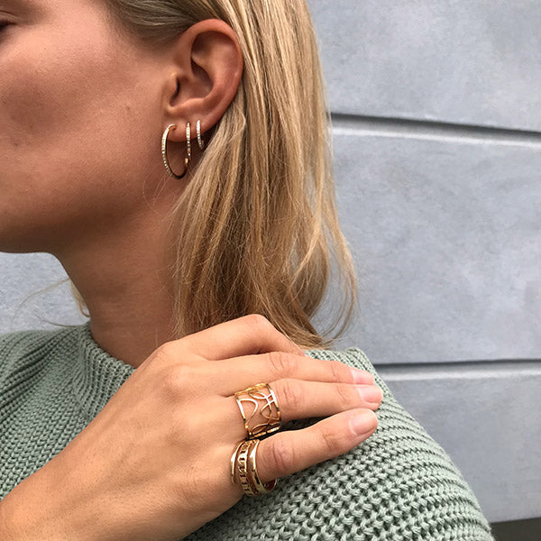 Woman wearing silver-plated ROBERTA small crystal semi-hoops, showcasing their Nordic-inspired chic and exclusive look, ideal for a casually trendy style.