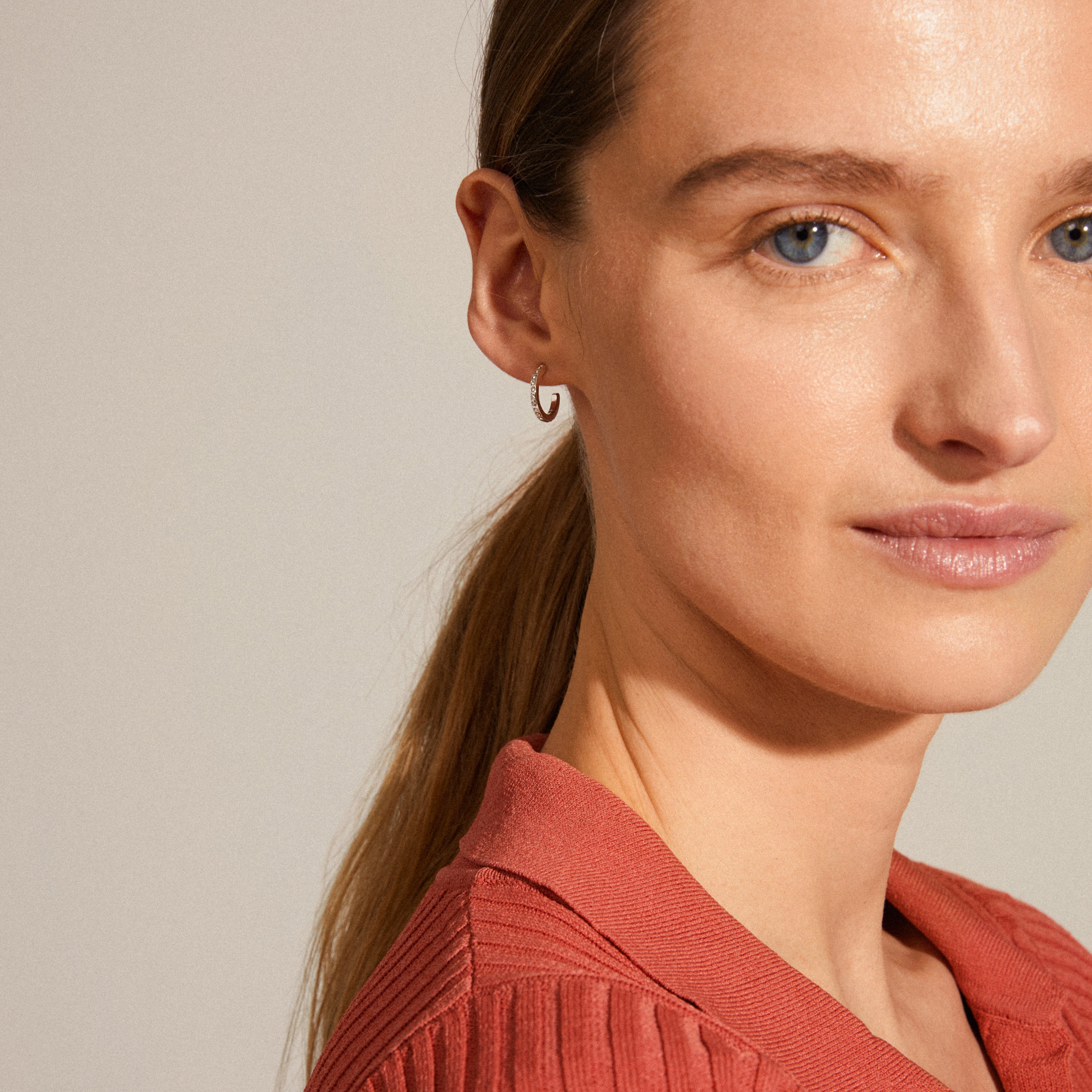 Woman wearing ROBERTA small crystal semi-hoops silver-plated, showcasing their elegant, sparkling design that complements her chic style.