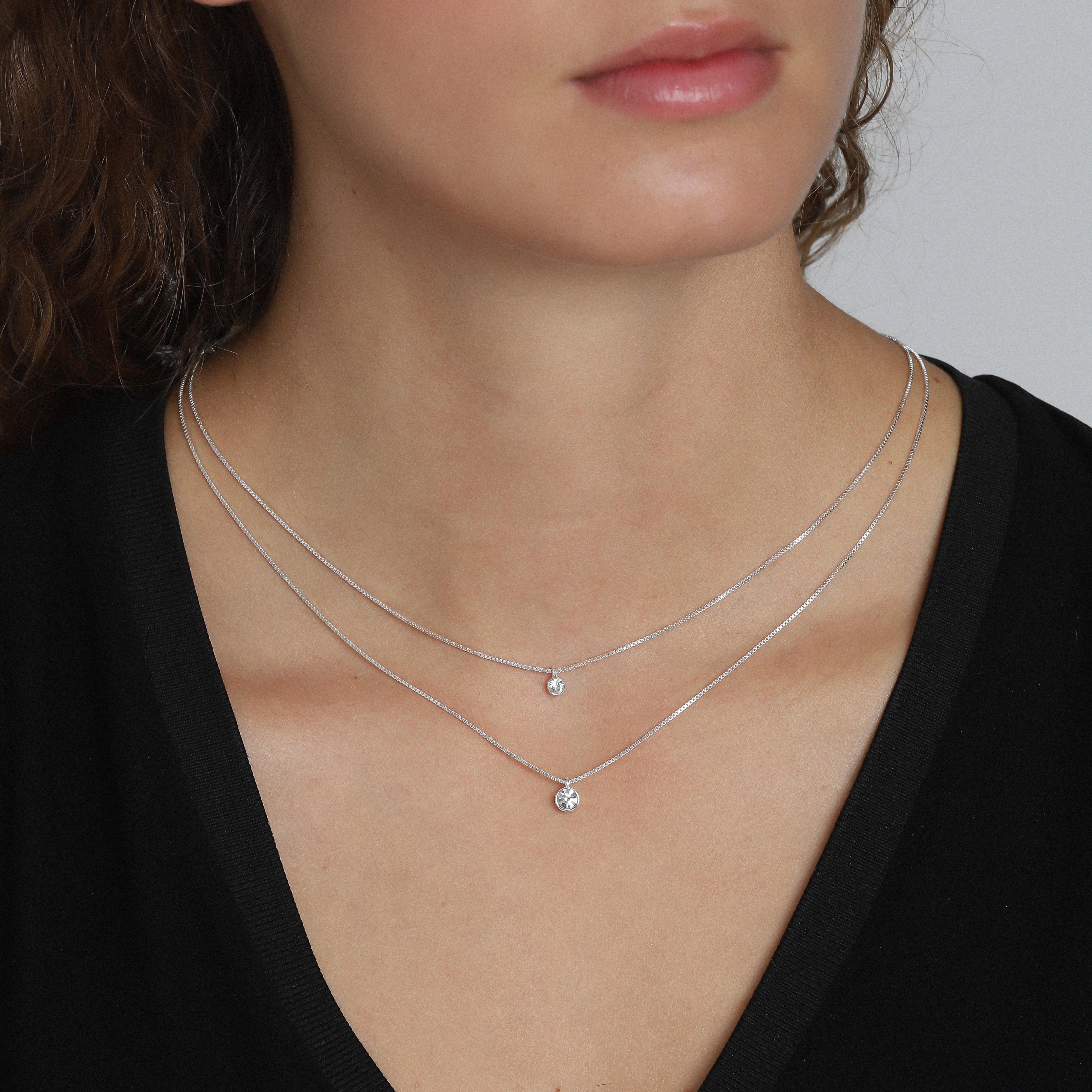 LUCIA 2-in-1 crystal necklace, silver-plated, worn by a woman, showcasing two sparkling crystal pendants on layered chains, ideal for stylish, trend-conscious individuals.