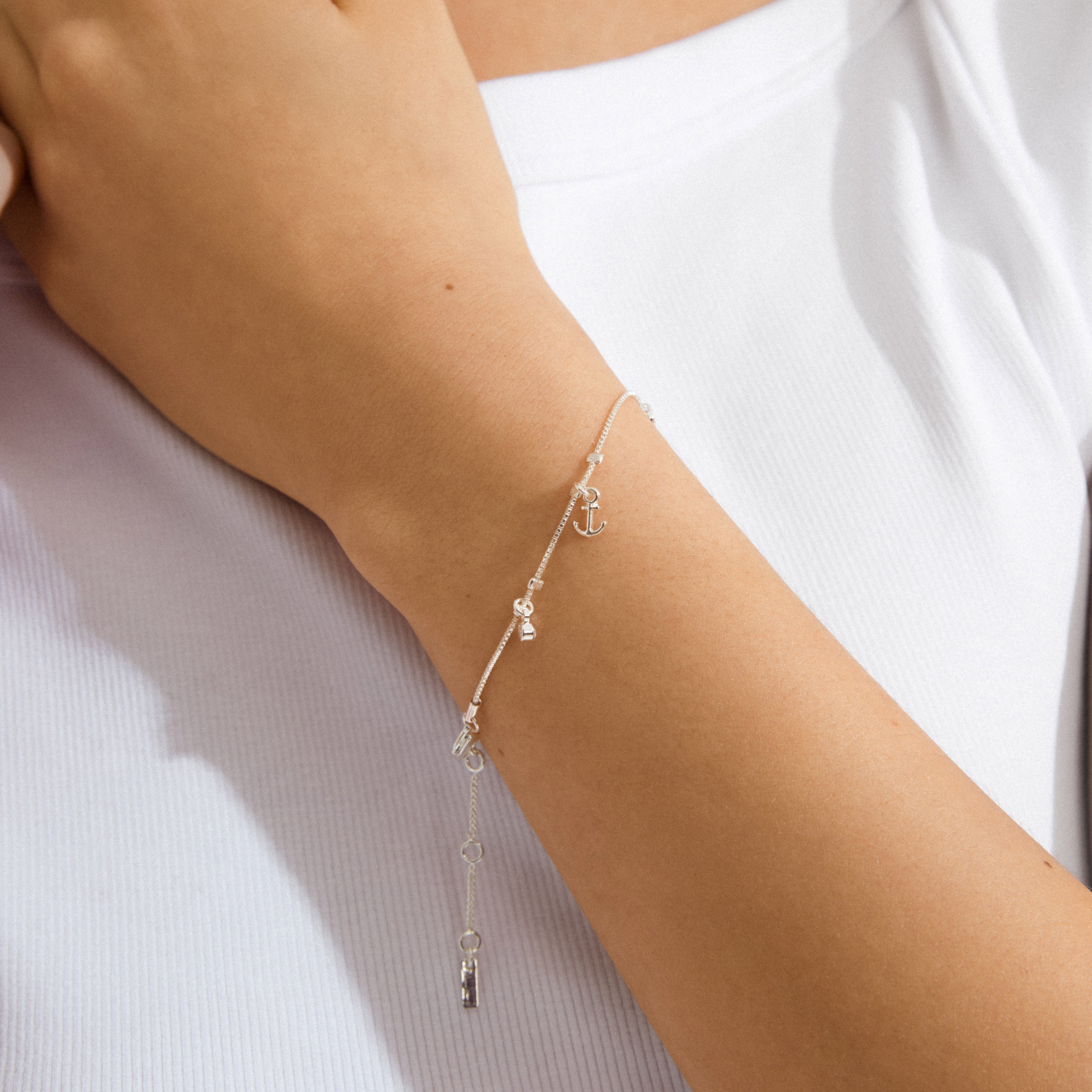 ANET crystal bracelet silver-plated with dangling charms: anchor, heart, and cross adorned with Preciosa crystals, elegantly displayed on a wrist wearing a rib-knit tank top.