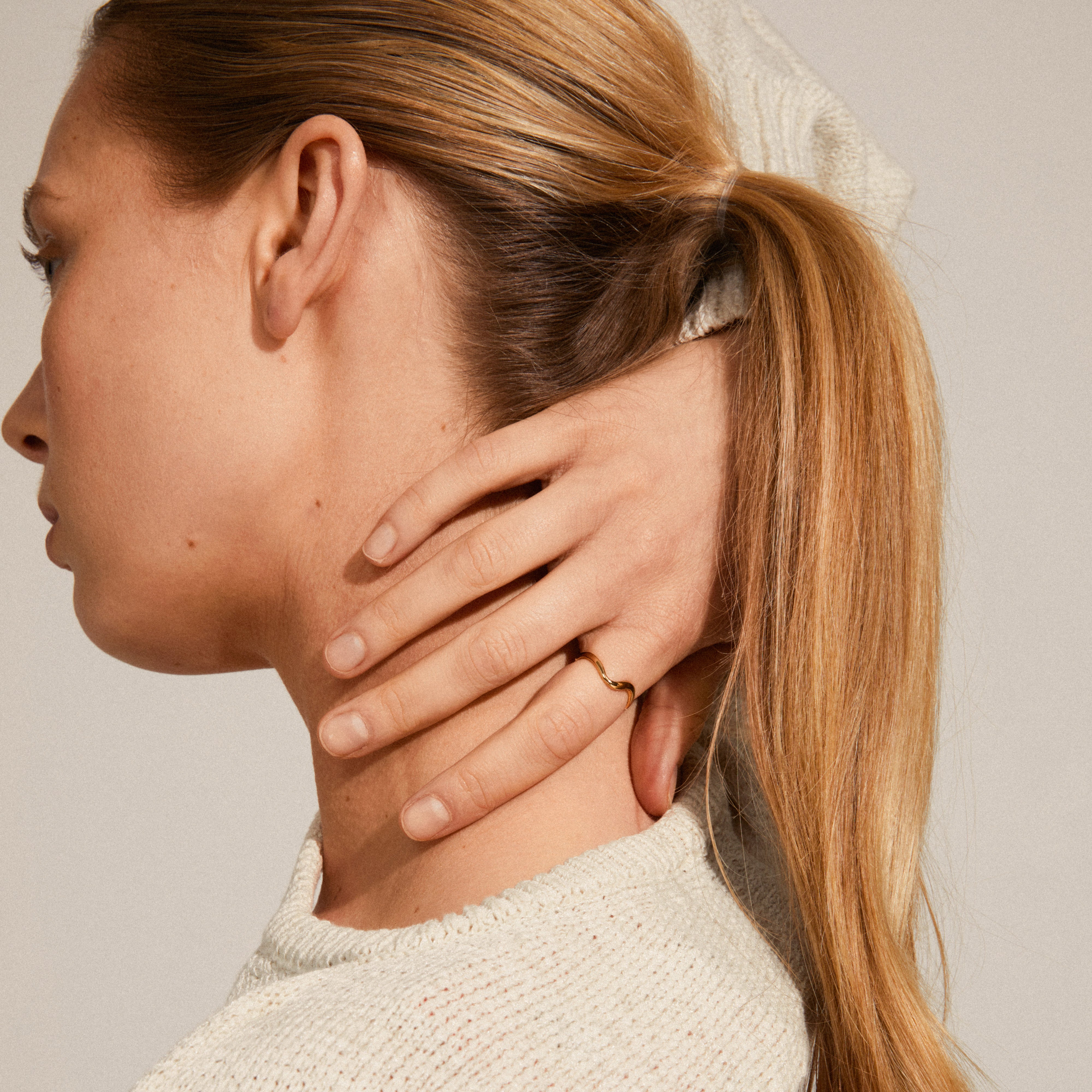 A woman displays the ALBERTE organic shape gold-plated ring on her finger, highlighting its minimalist and handcrafted design.