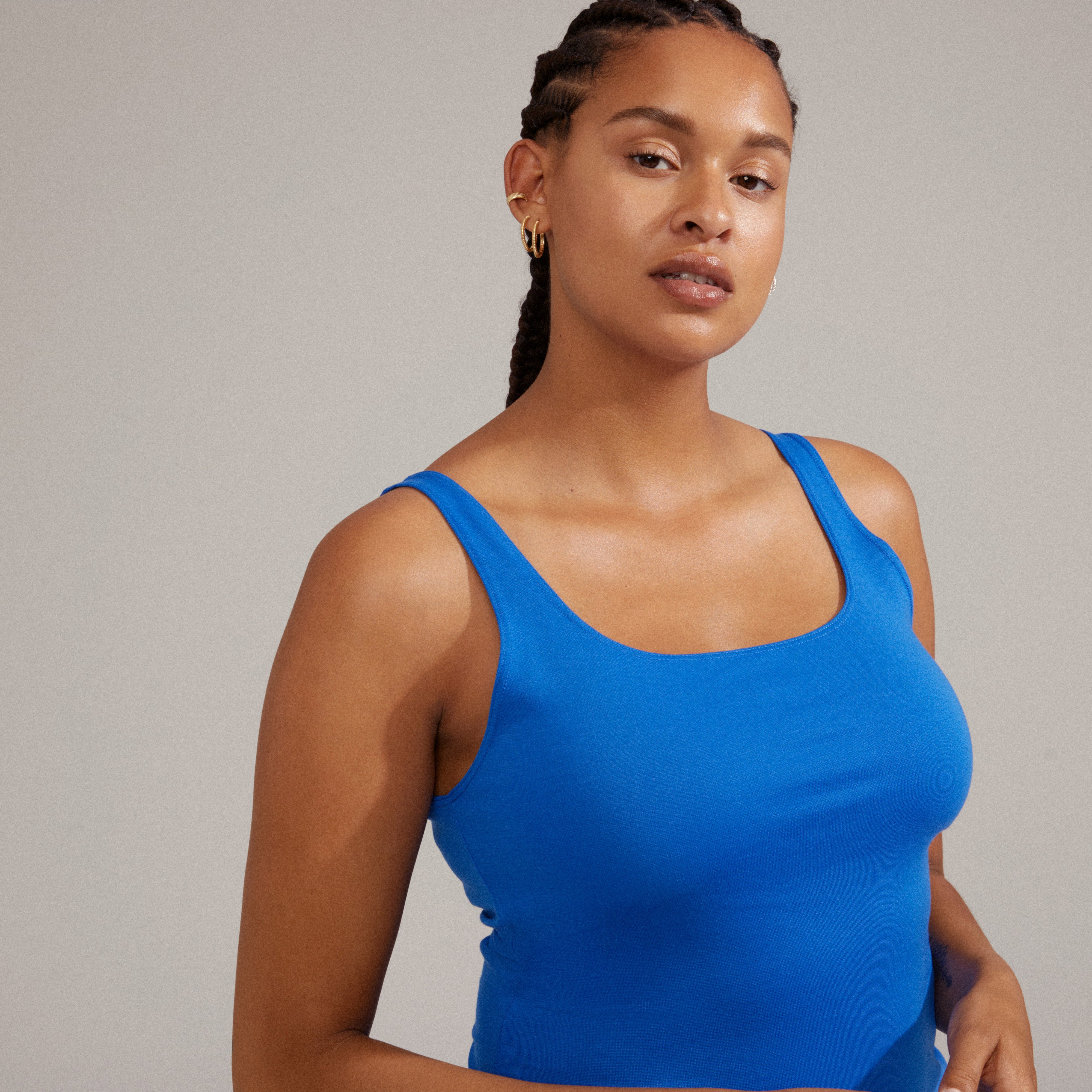 XENA hoop & cuff earrings gold-plated, showcased on a woman with braided hair wearing a blue tank top, highlighting the earrings' fluted style and adjustable design.