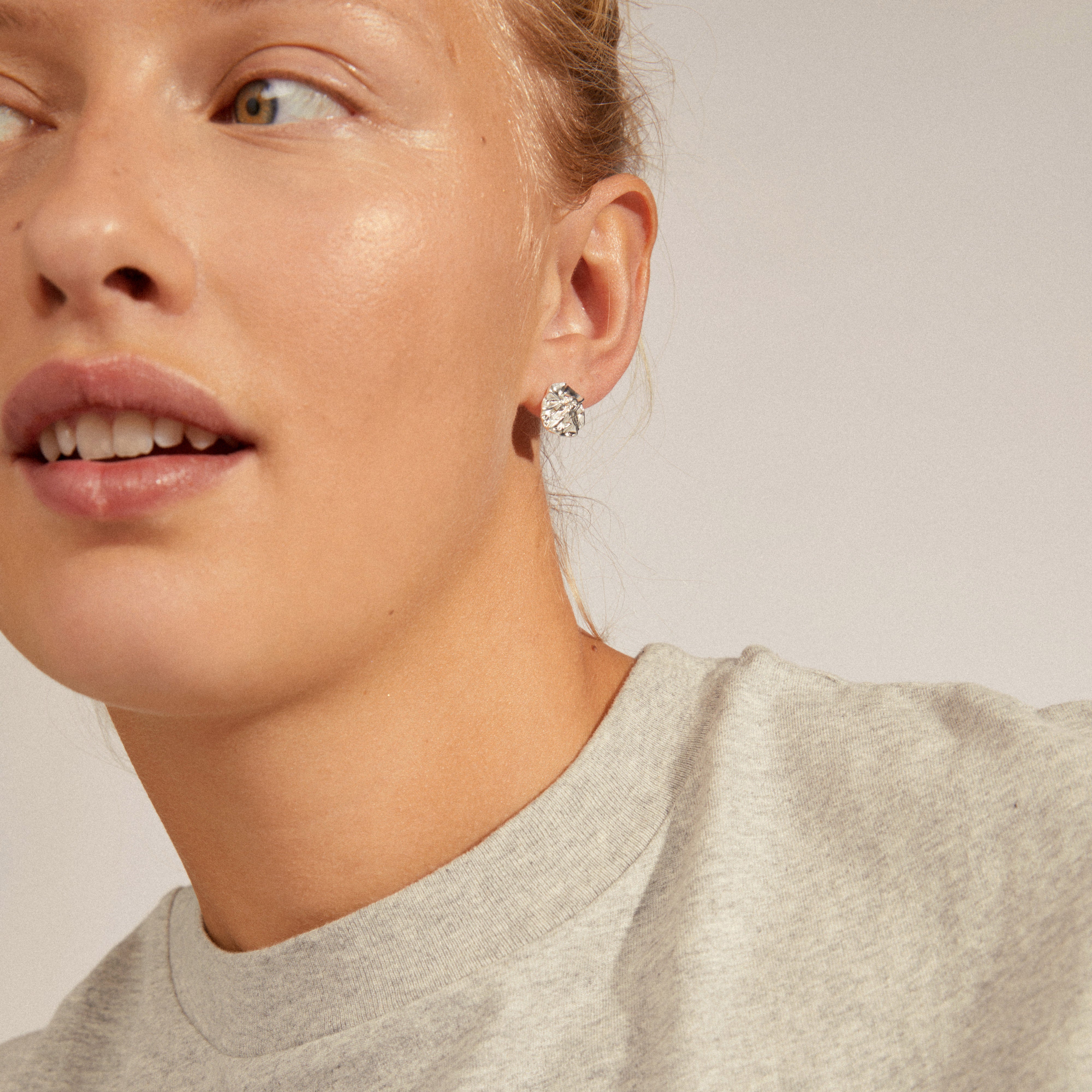 Woman wearing silver-plated WILLPOWER earrings with wavy, organic design, highlighting their timeless, water-inspired elegance. Perfect for adding style to a basic outfit.
