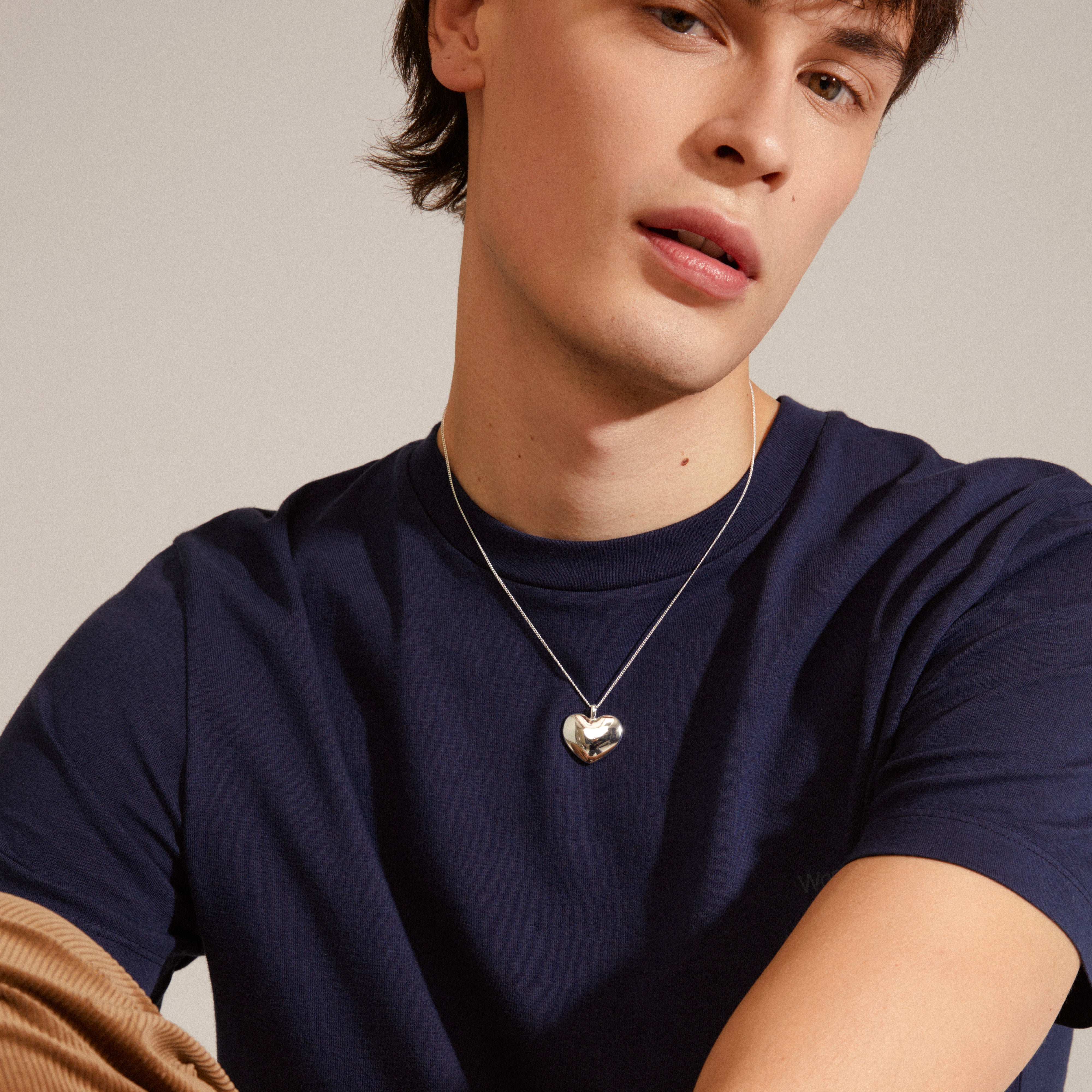 SOPHIA heart pendant necklace, silver-plated, worn by a man in a blue shirt. Features a classic design, adjustable length, from Pilgrim's recycled collection.