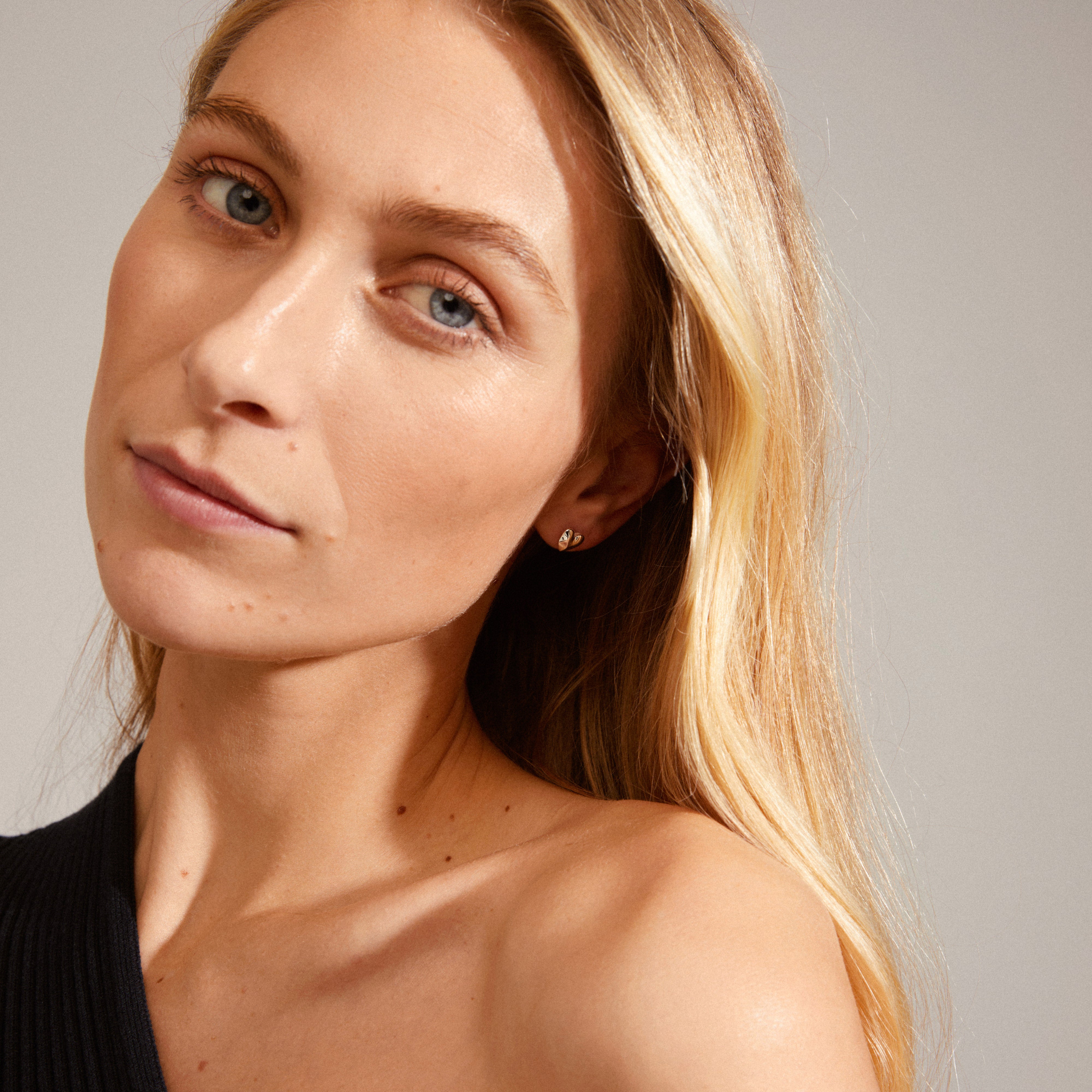 SOPHIA heart earrings, silver-plated, elegantly adorn a woman's ear, highlighting Pilgrim's Scandinavian-inspired, sustainable jewelry design.