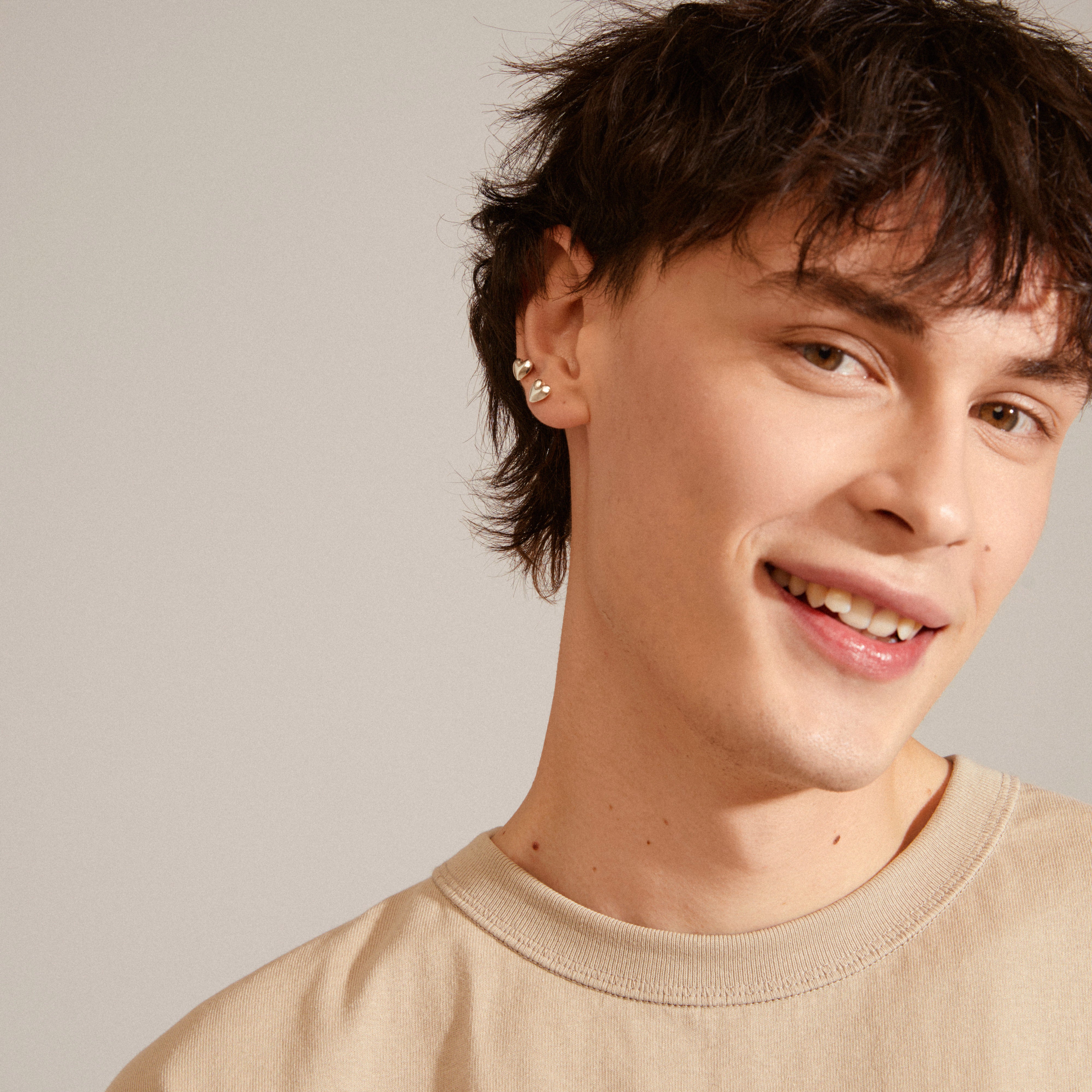 SOPHIA heart earrings silver-plated from Pilgrim, worn by a smiling man; elegant, shiny, and crafted from 93% recycled materials for a romantic look.