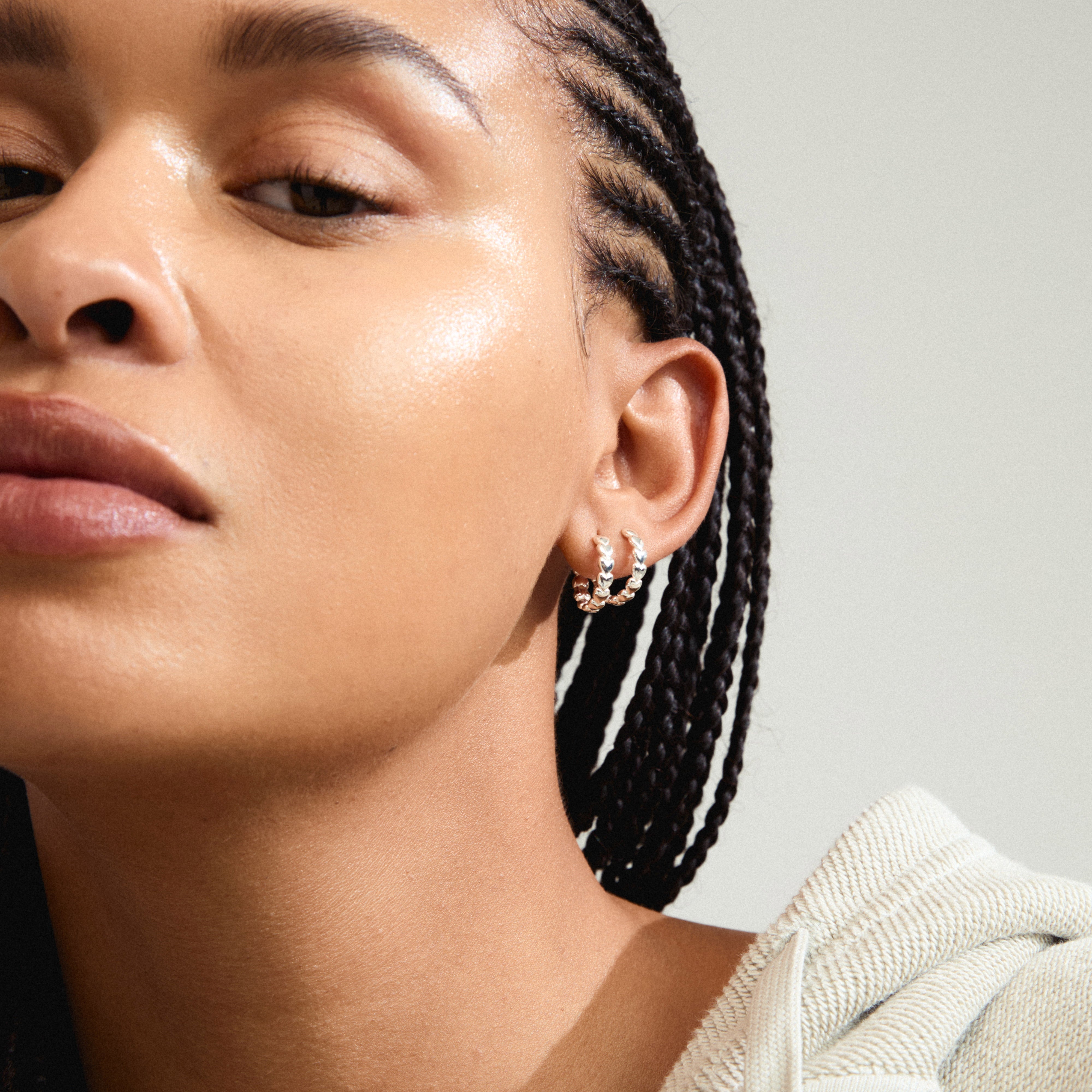 MAEVE hoop earrings silver-plated with heart pattern, worn by a woman with braided hair and earrings, showcasing Pilgrim's timeless Danish design.