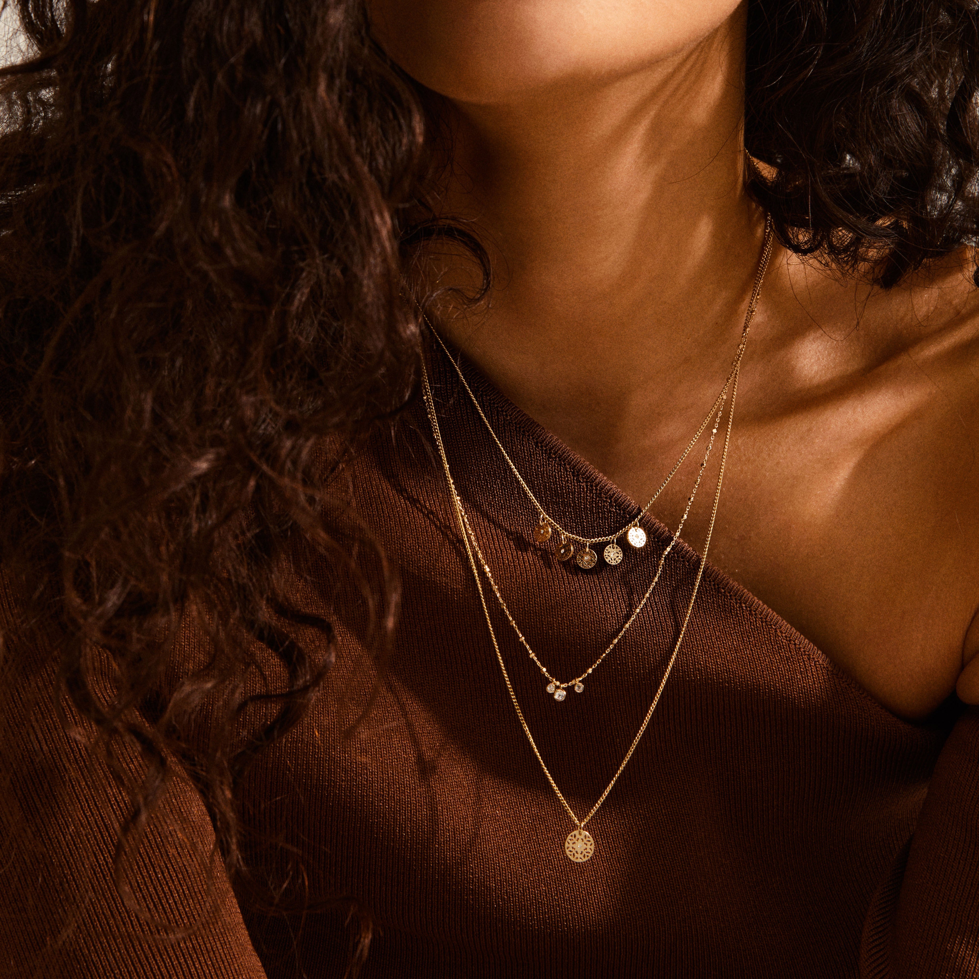 CAROL layered necklace 3-in-1 gold-plated, featuring three delicate chains, elegantly worn by a woman, showcasing a chic, urban style.