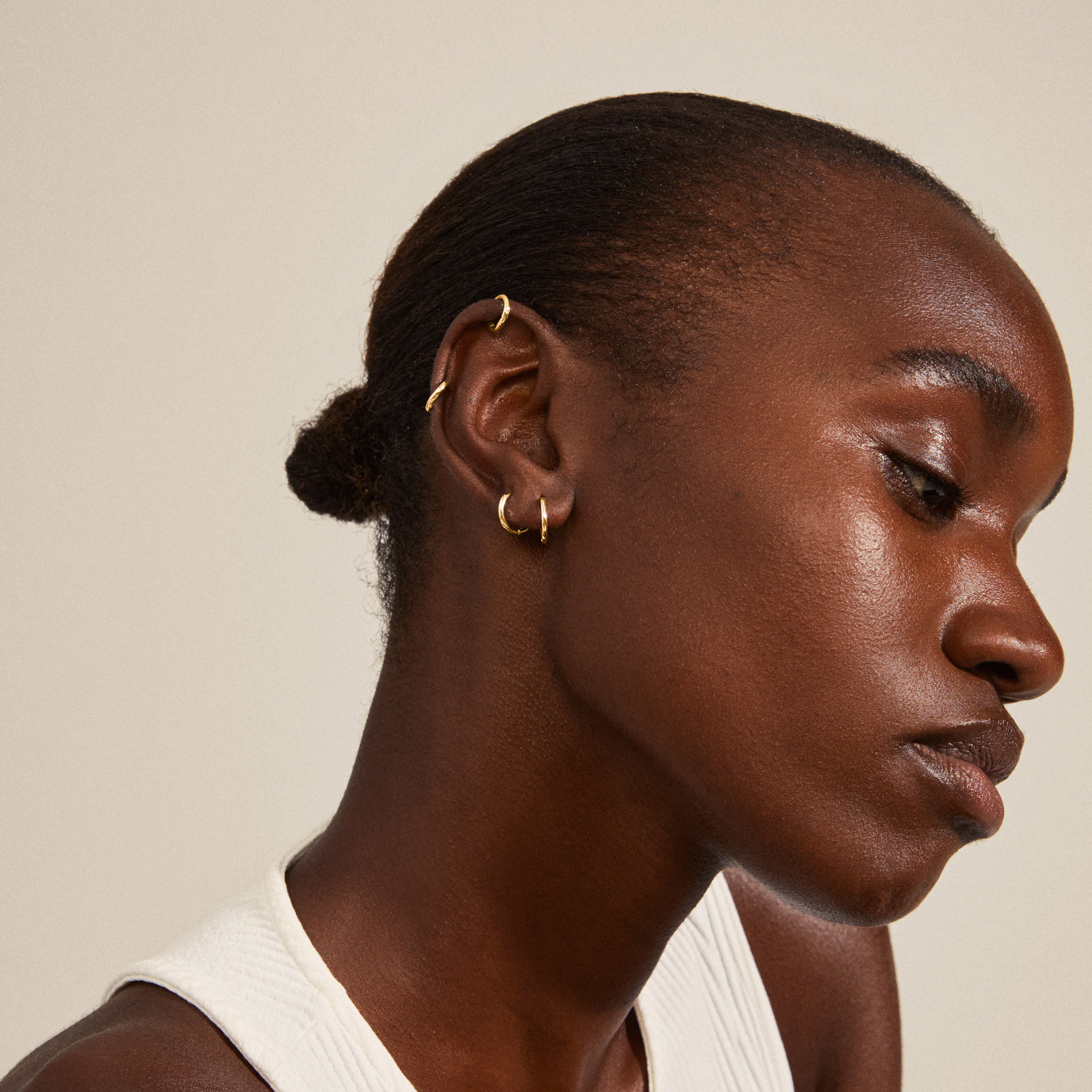 ARIELLA gold-plated hoop earrings 2-in-1 set displayed on a woman with brown hair, showcasing their chunky, shiny design and small huggie style.