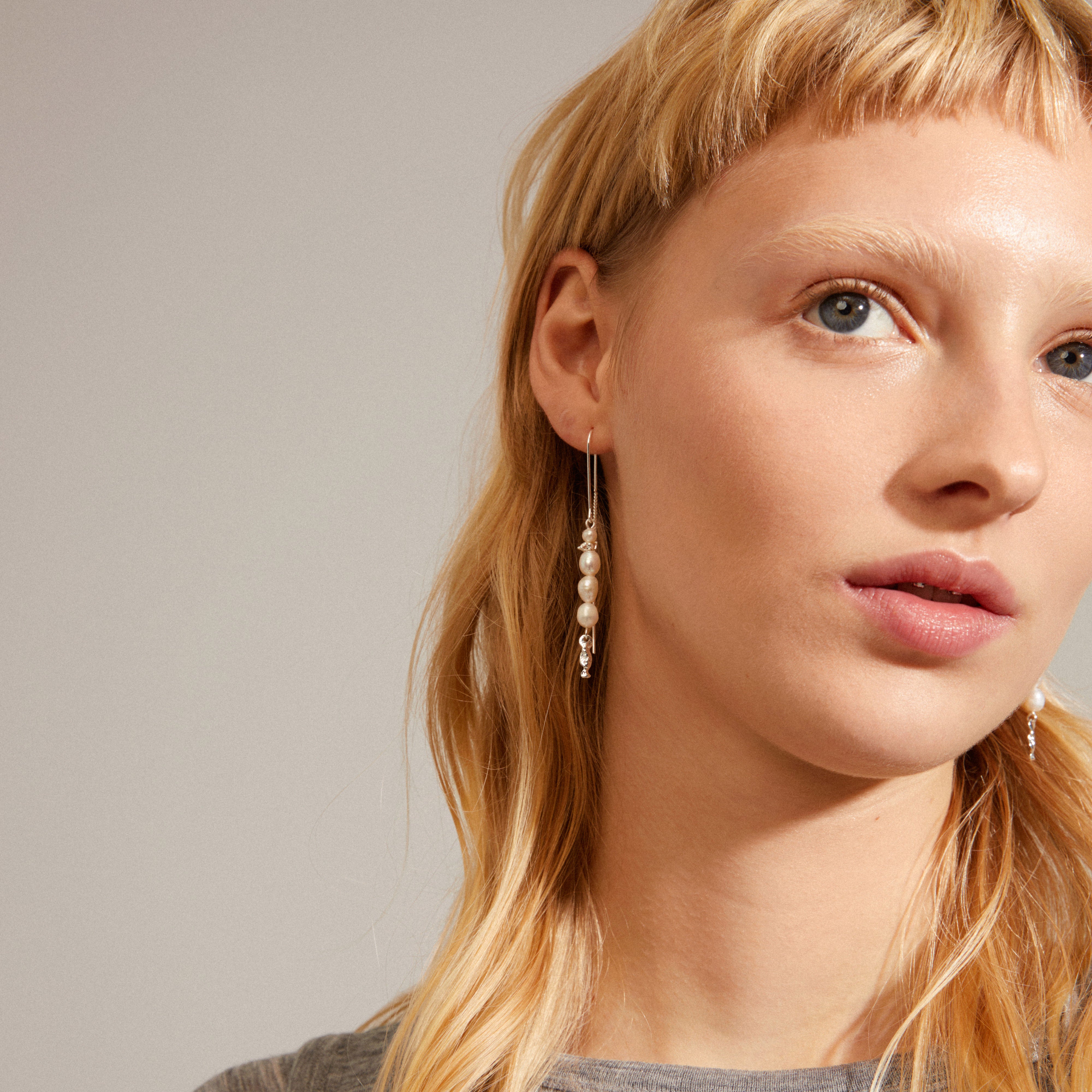 BERTHE pearl chain earrings, silver-plated, featuring genuine freshwater pearls with organic silver detailing, worn by a woman with blonde hair.