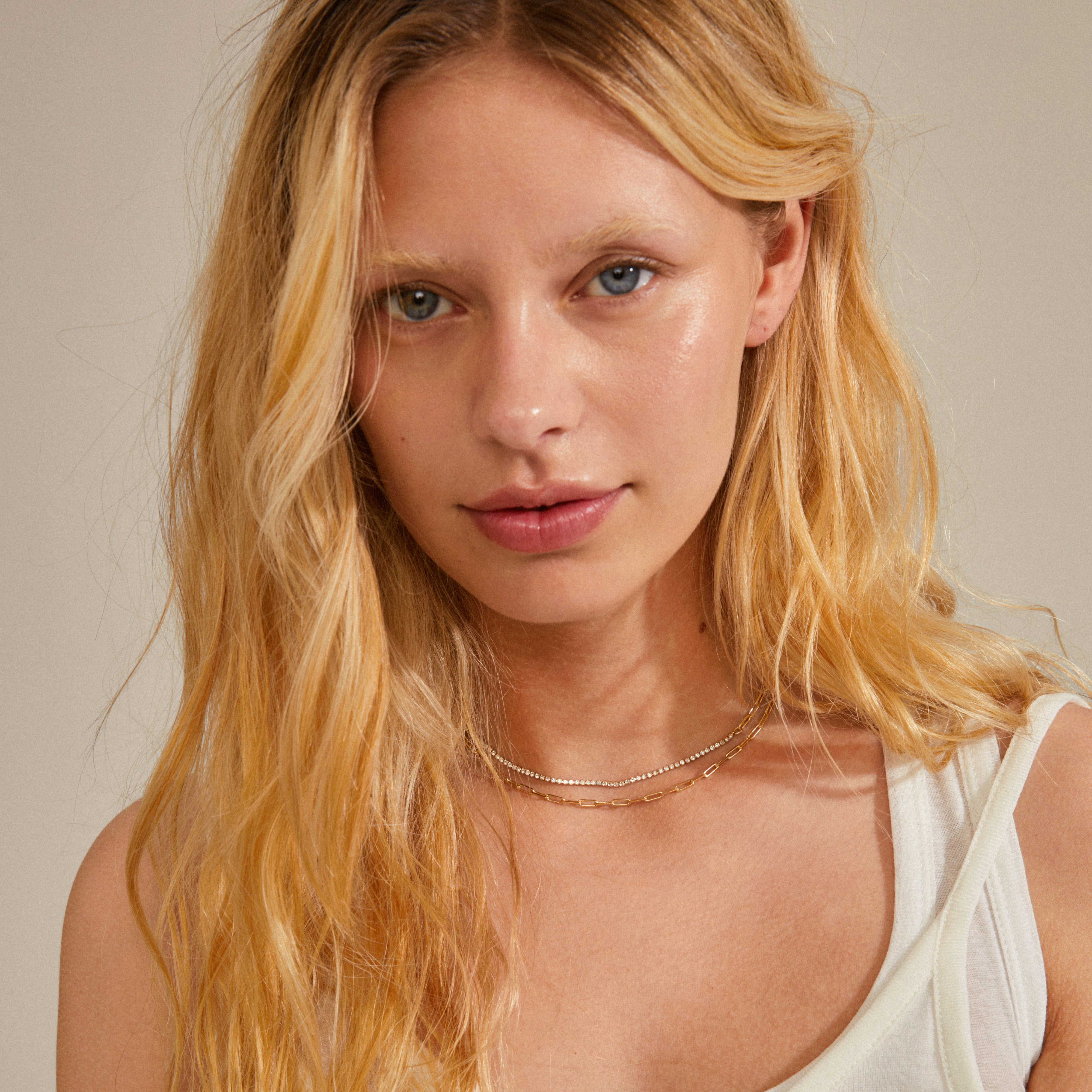ROWAN necklace, 2-in-1, gold-plated, featuring sparkling crystals and delicate cable chains, worn by a woman with blonde hair, showcasing its elegance and layering style.