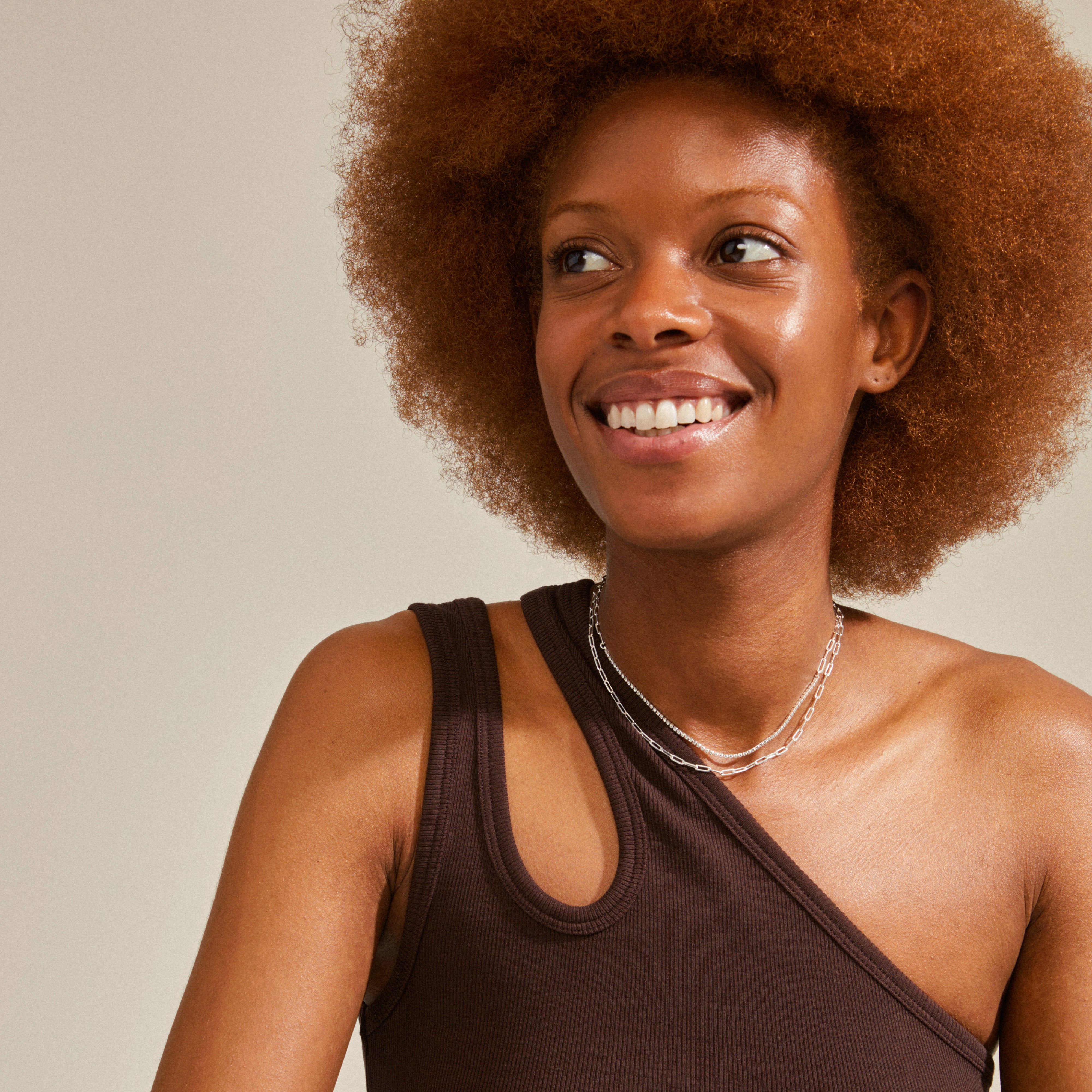 Woman smiling while wearing Pilgrim's ROWAN 2-in-1 silver-plated necklace, featuring delicate chains and sparkling crystals, styled in a trendy layered look.