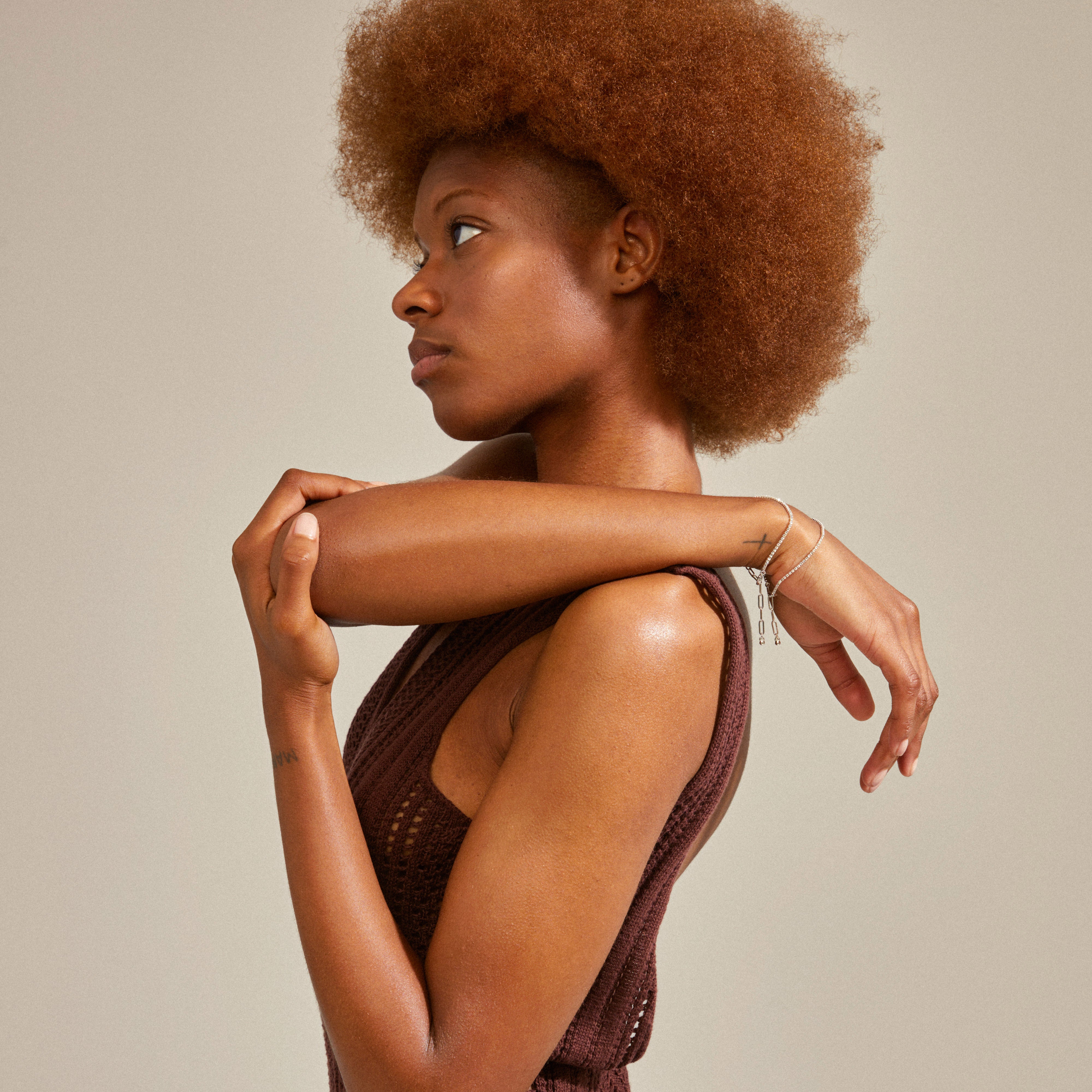 A woman wearing a brown knitted swimsuit showcases the silver-plated ROWAN crystal bracelet, 2-in-1, featuring a layered design with Preciosa crystals and a cable chain.