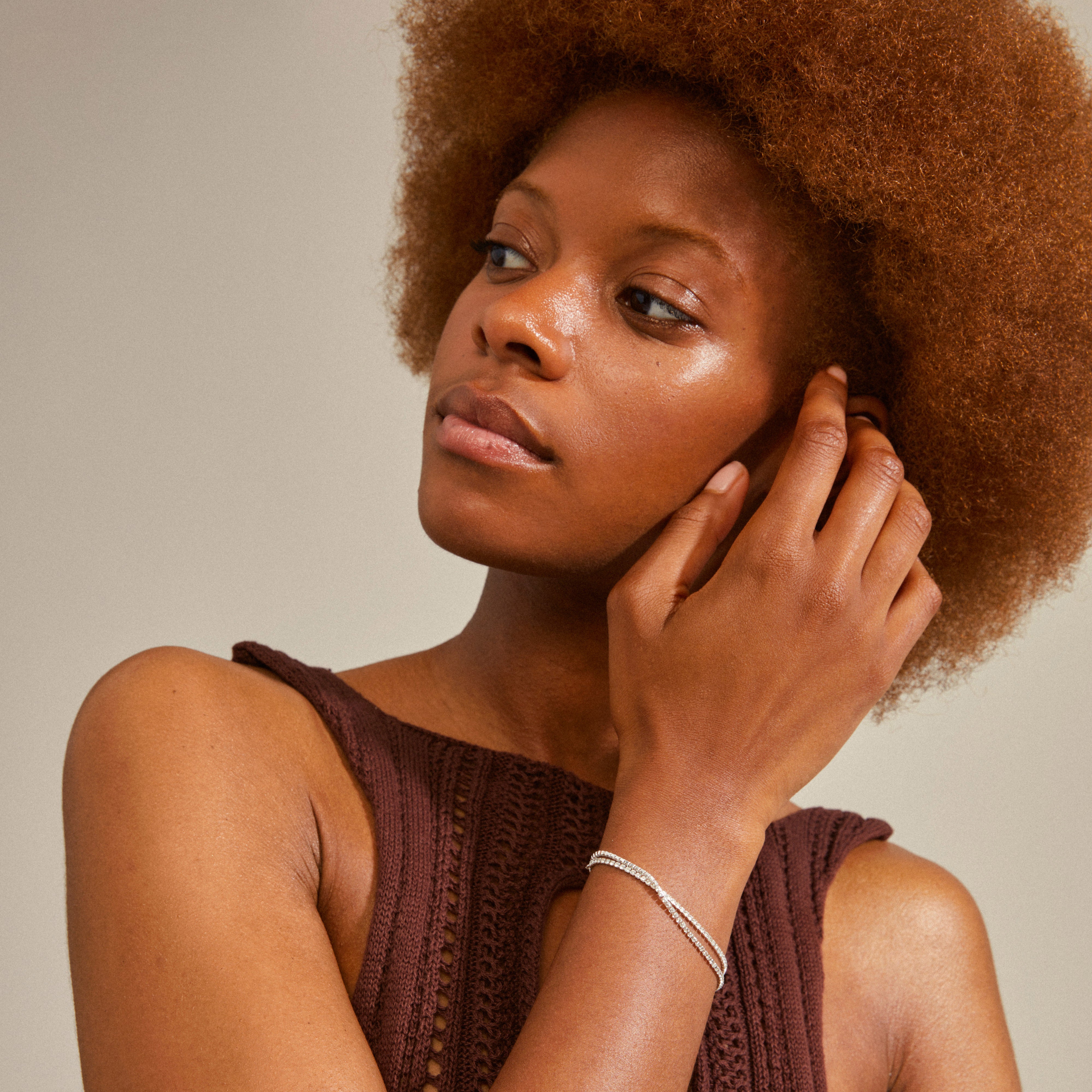 Woman wearing ROWAN crystal bracelet, 2-in-1, silver-plated, featuring two chains with Preciosa crystals and a classic cable chain, hand on face.