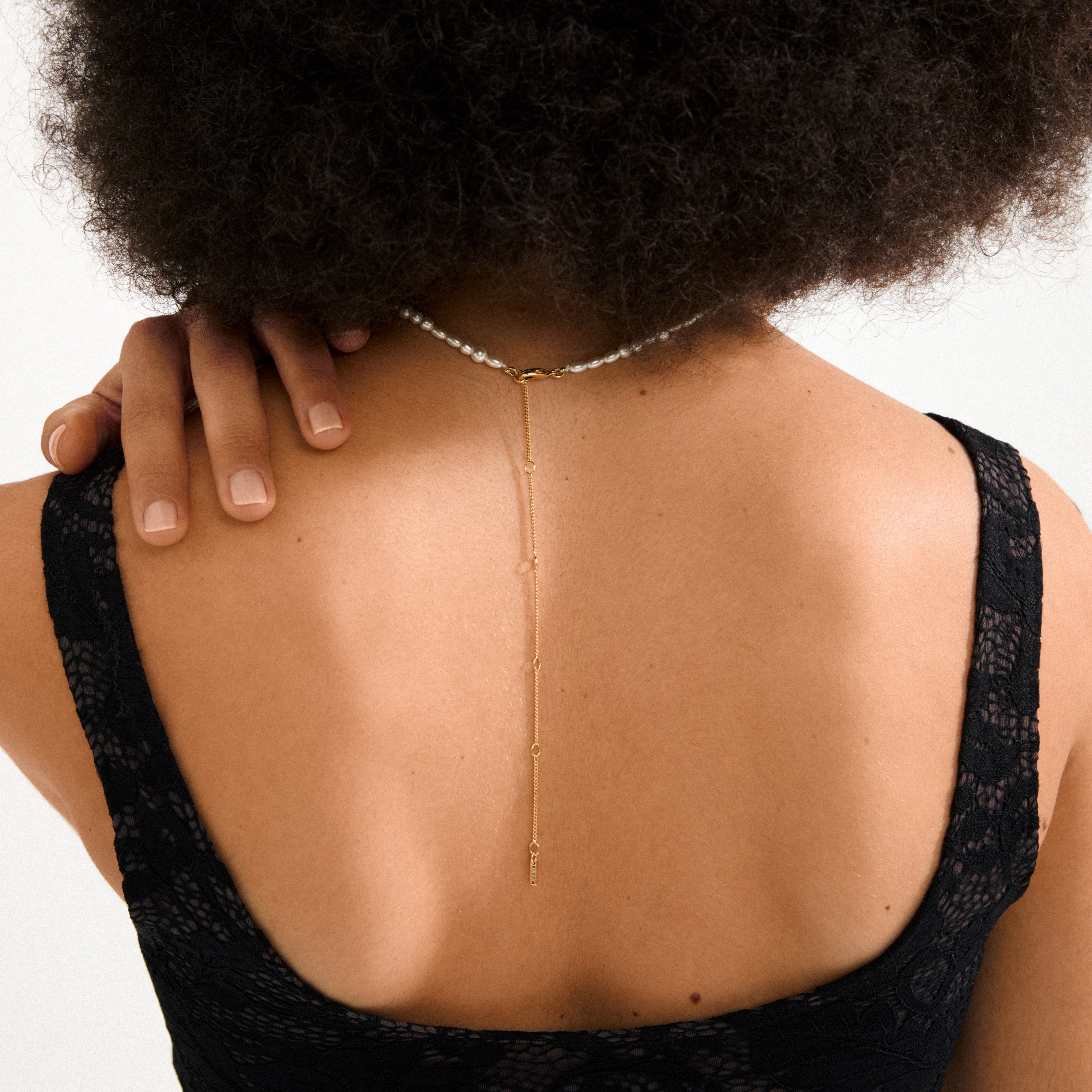 ELLANA gold-plated necklace featuring freshwater pearls and mother-of-pearl glass beads, elegantly worn by a woman, showcasing its timeless, modern design.
