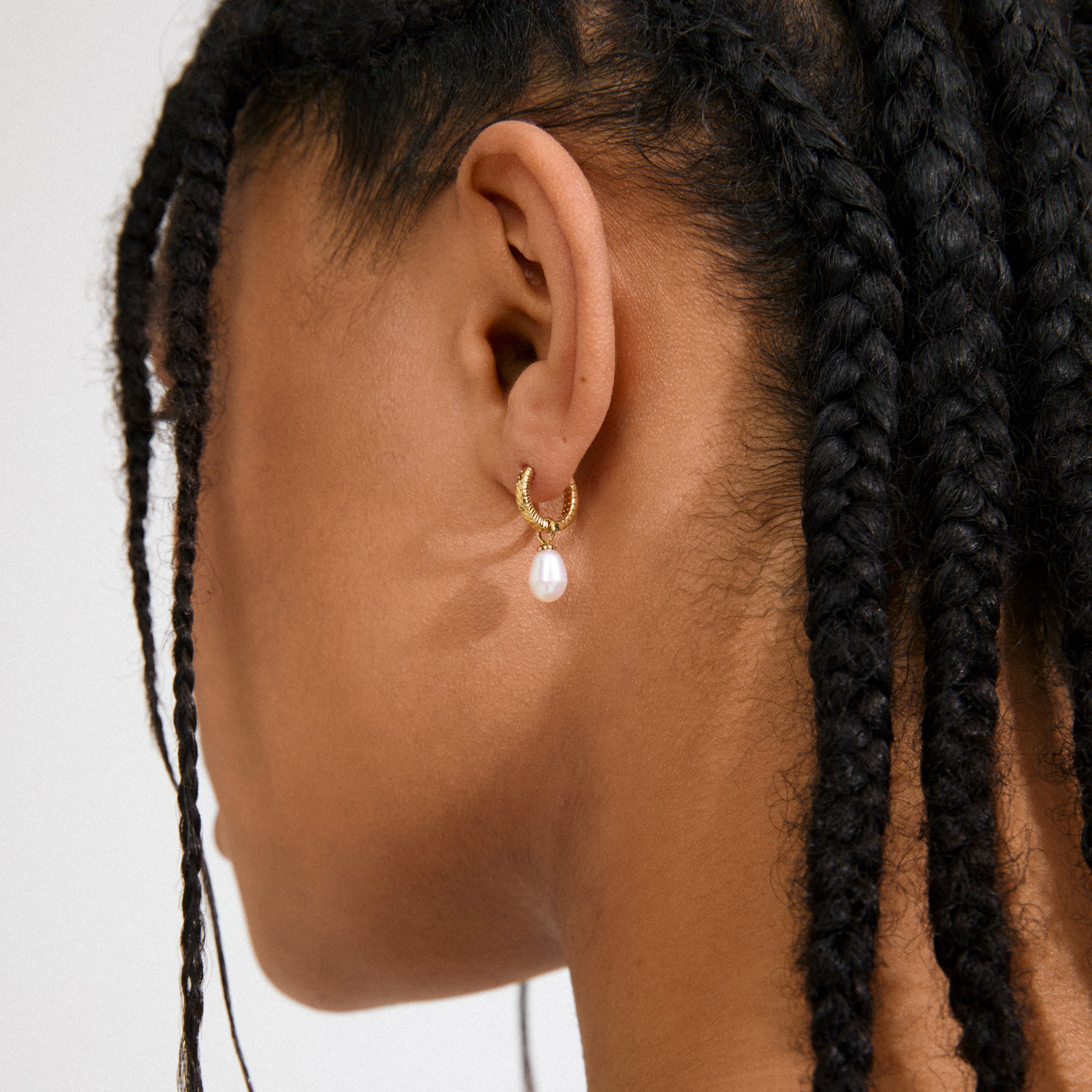 ELLIANA earrings: Gold-plated hoops with braided texture and freshwater pearls, featuring easy-click clasps. Versatile and elegant, perfect for enhancing trendy, personal style.