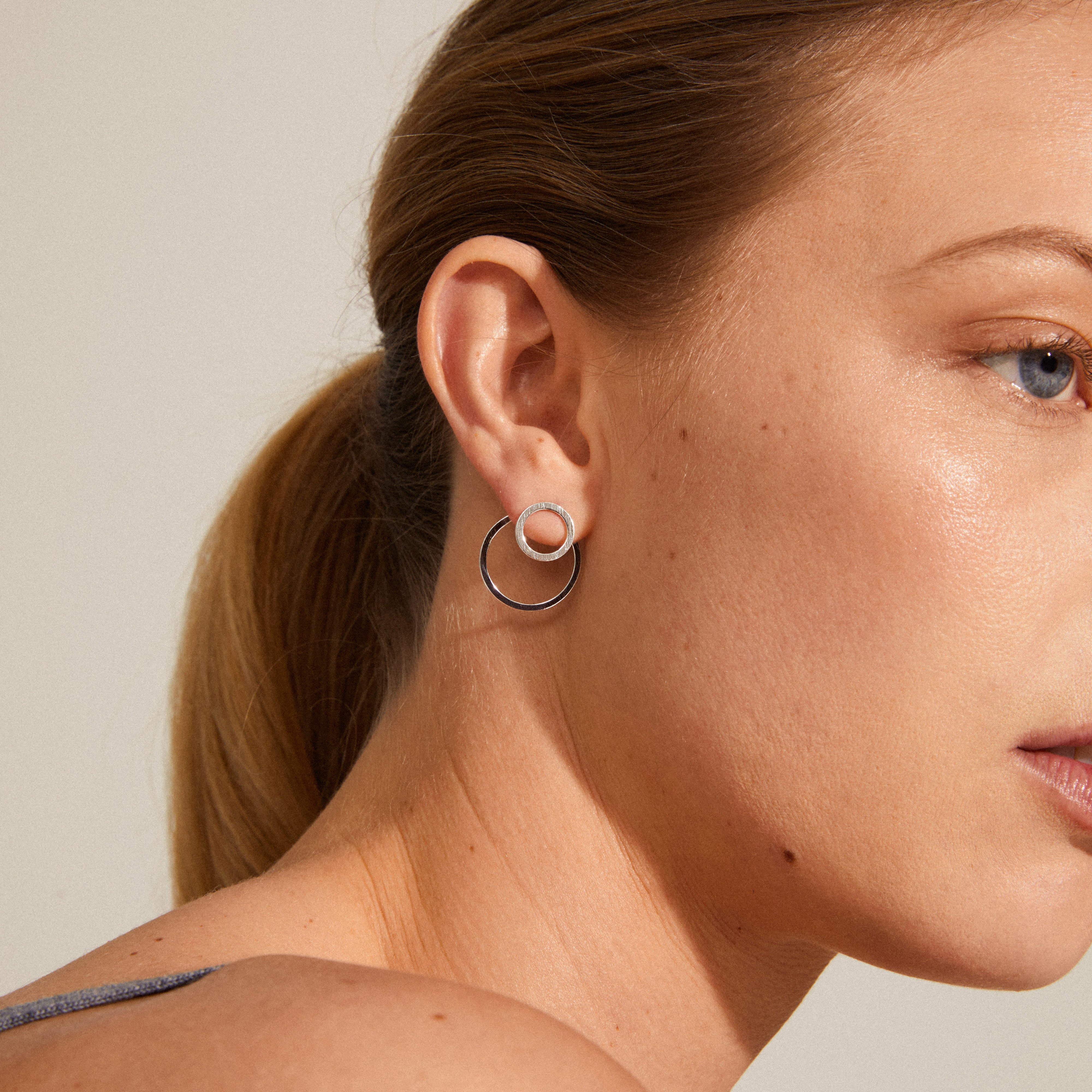 ZOOEY 2-in-1 earrings silver-plated, featuring a rustic embossed pattern, with a large circle behind and a small circle in front of the earlobe.