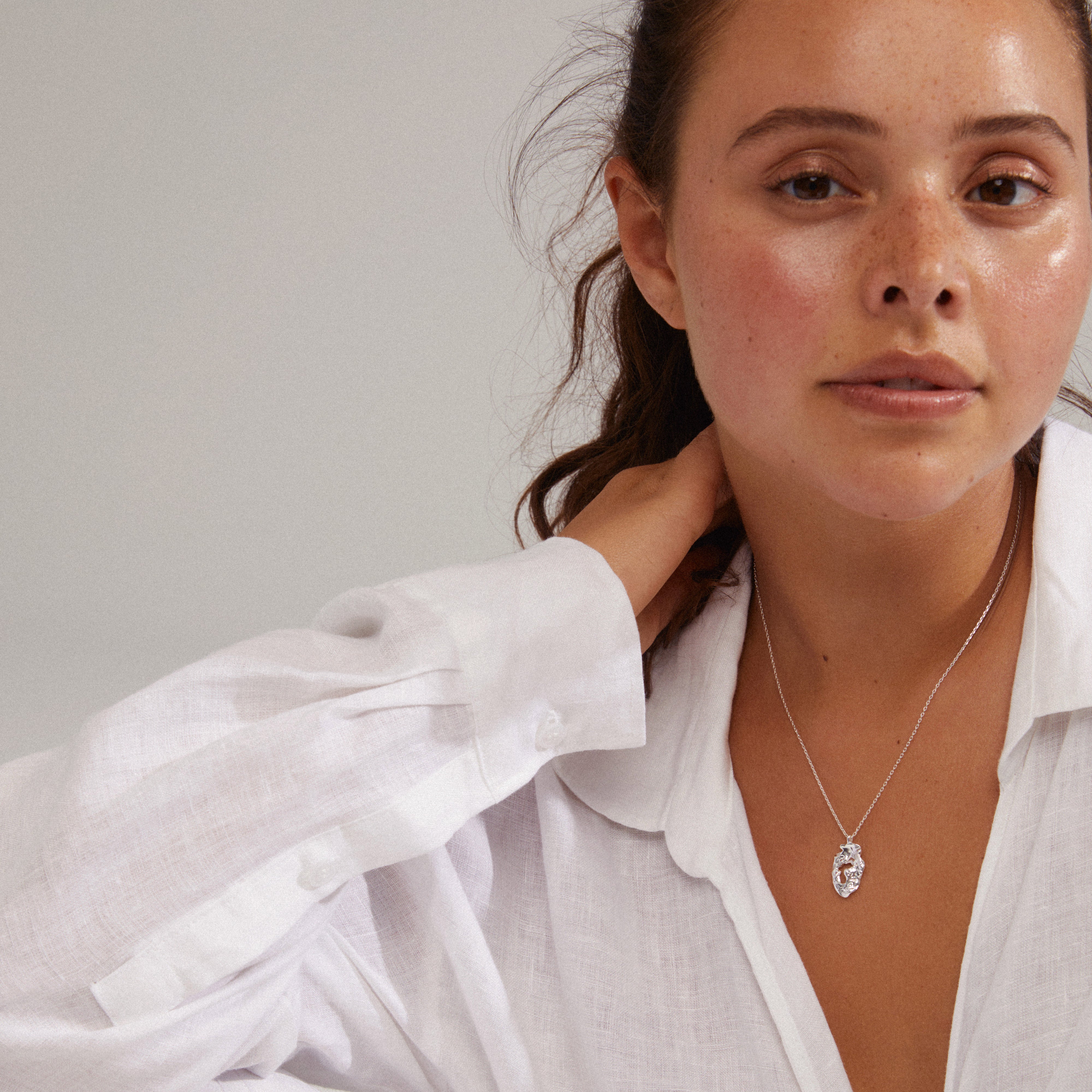 QUINN organic shaped pendant necklace, silver-plated, worn by a woman. Features small Preciosa crystal accents, exuding a unique handcrafted, nature-inspired feel.
