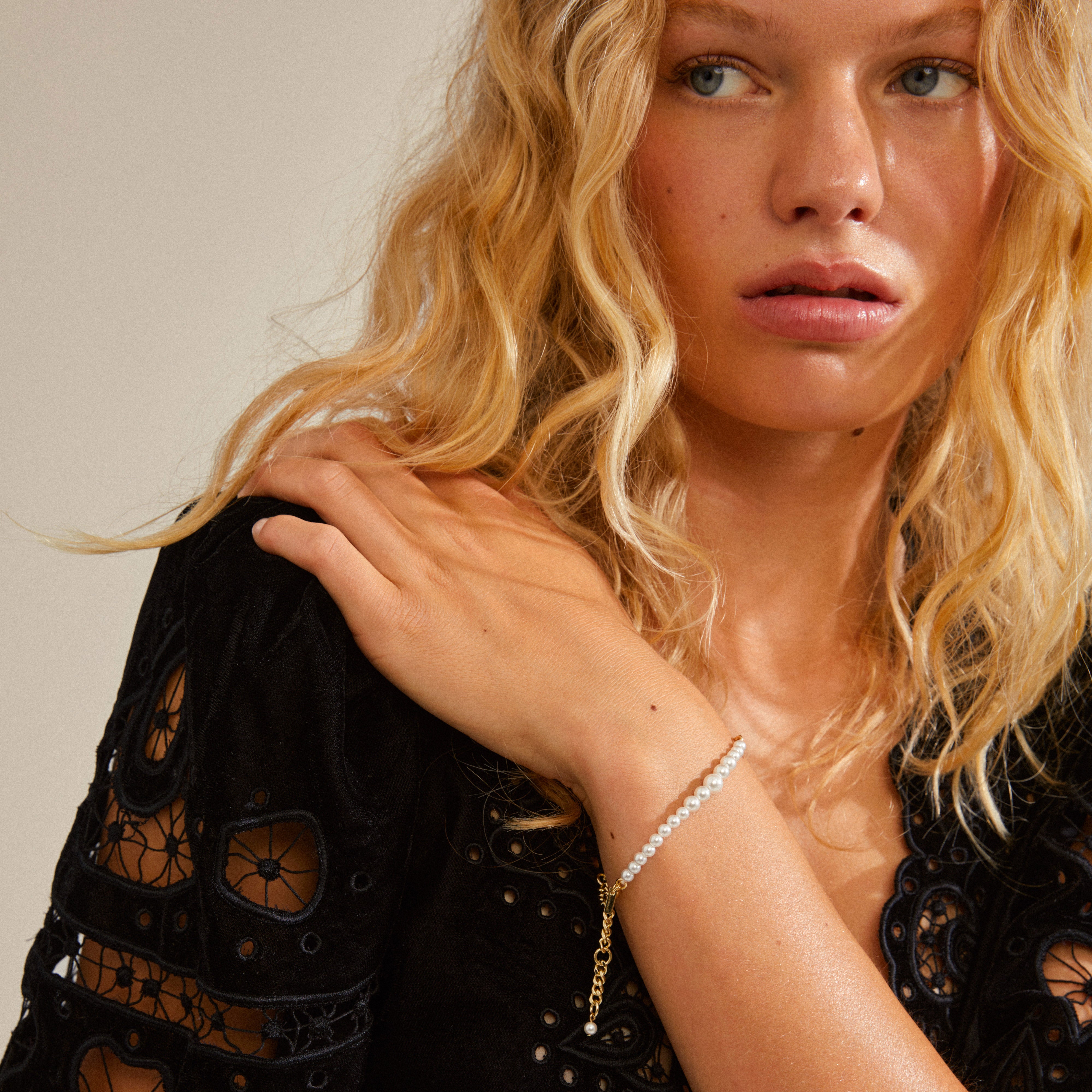RELANDO pearl bracelet gold-plated showcased on a woman's wrist, highlighting its elegant white glass pearls and chunky curb chain design, reflecting Pilgrim's timeless style.