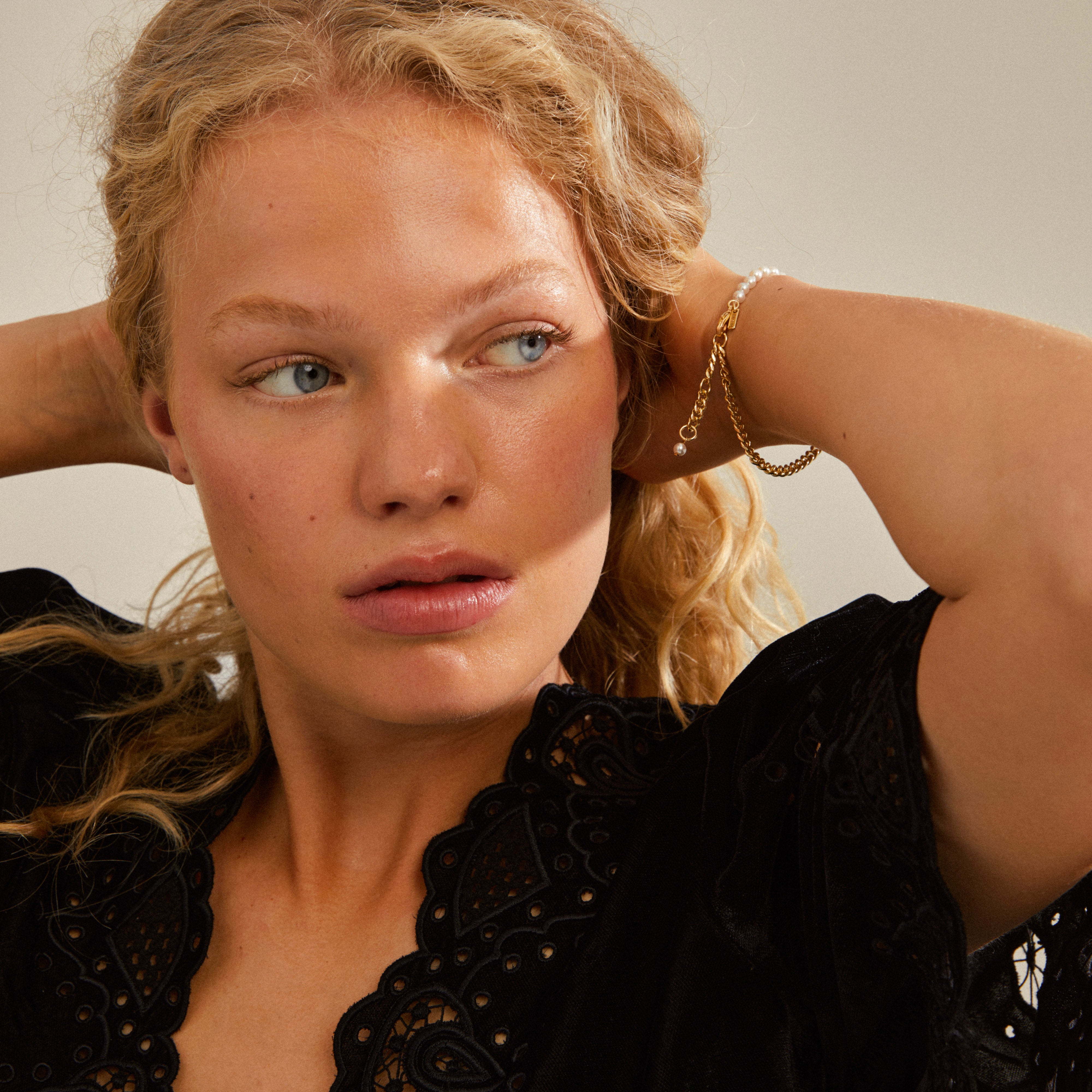 RELANDO pearl bracelet gold-plated on a woman, showcasing white glass pearls and a chunky curb chain for an elegant, urban edge.