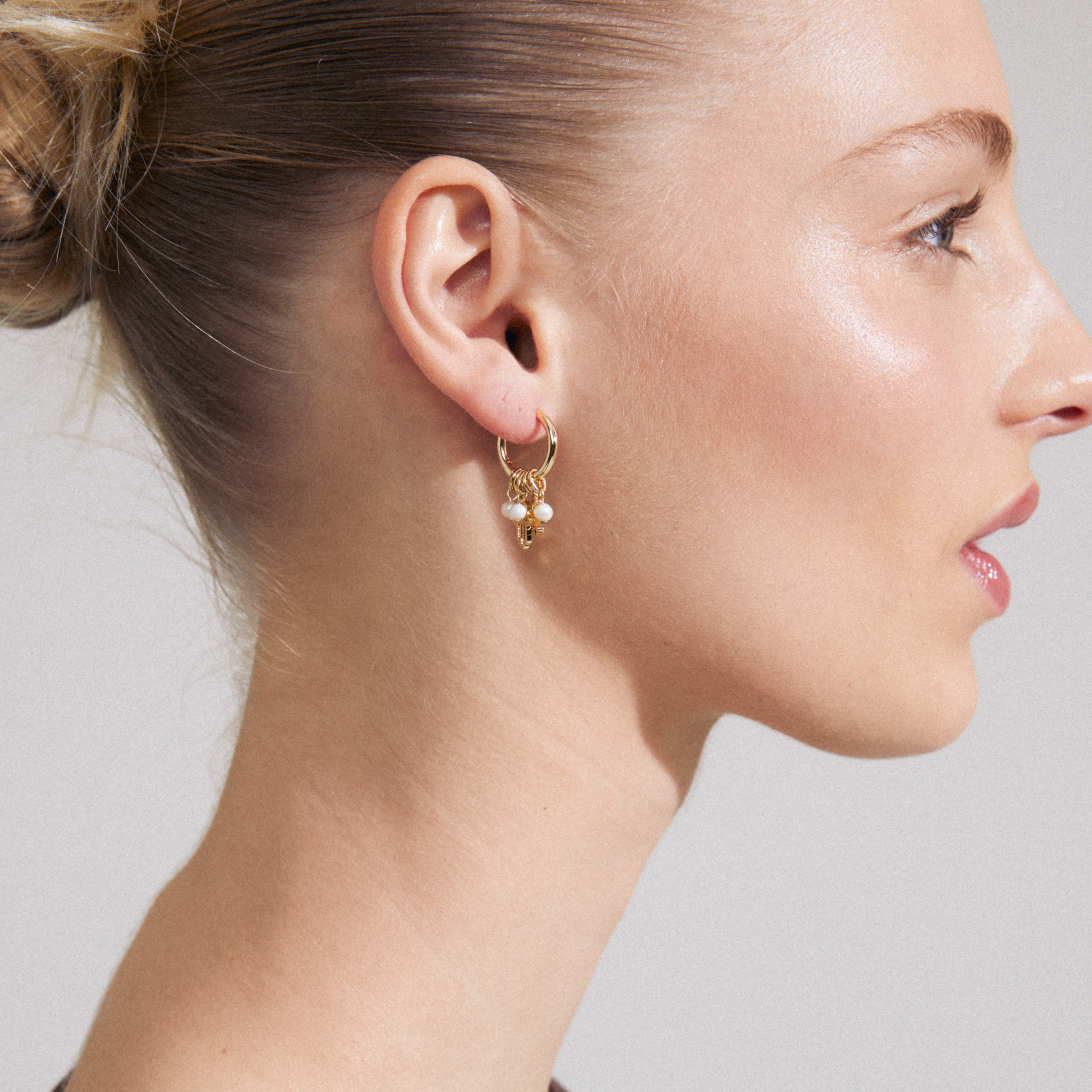 PRUCENCE gold-plated earrings by Pilgrim feature charming hoops with moon, Hamsa, pearls, and crystals, offering a romantic, adventurous touch.