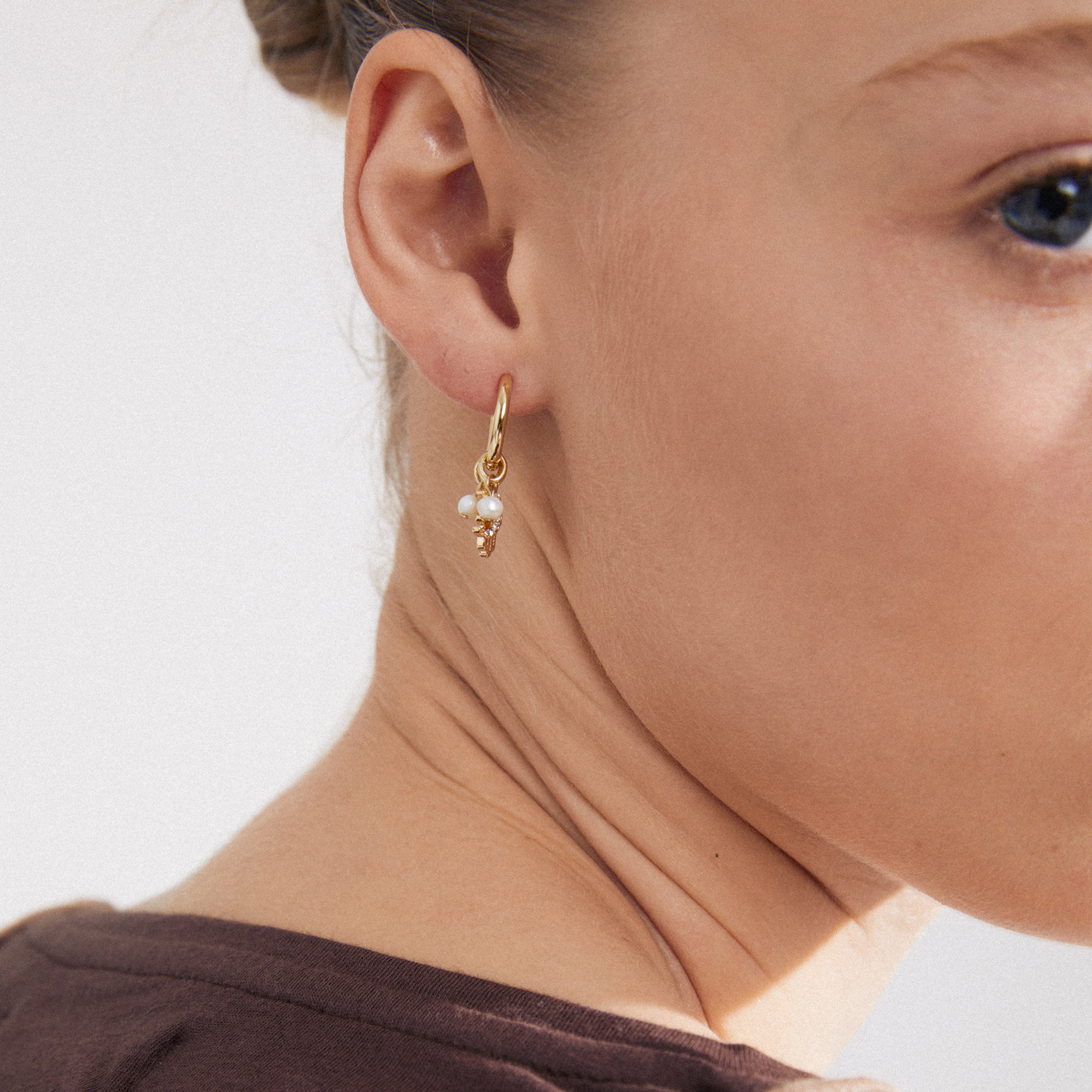 PRUCENCE gold-plated earrings with moon and Hamsa charms, freshwater pearl, and Preciosa crystals, worn by a woman, highlighting elegance and Scandinavian craftsmanship.