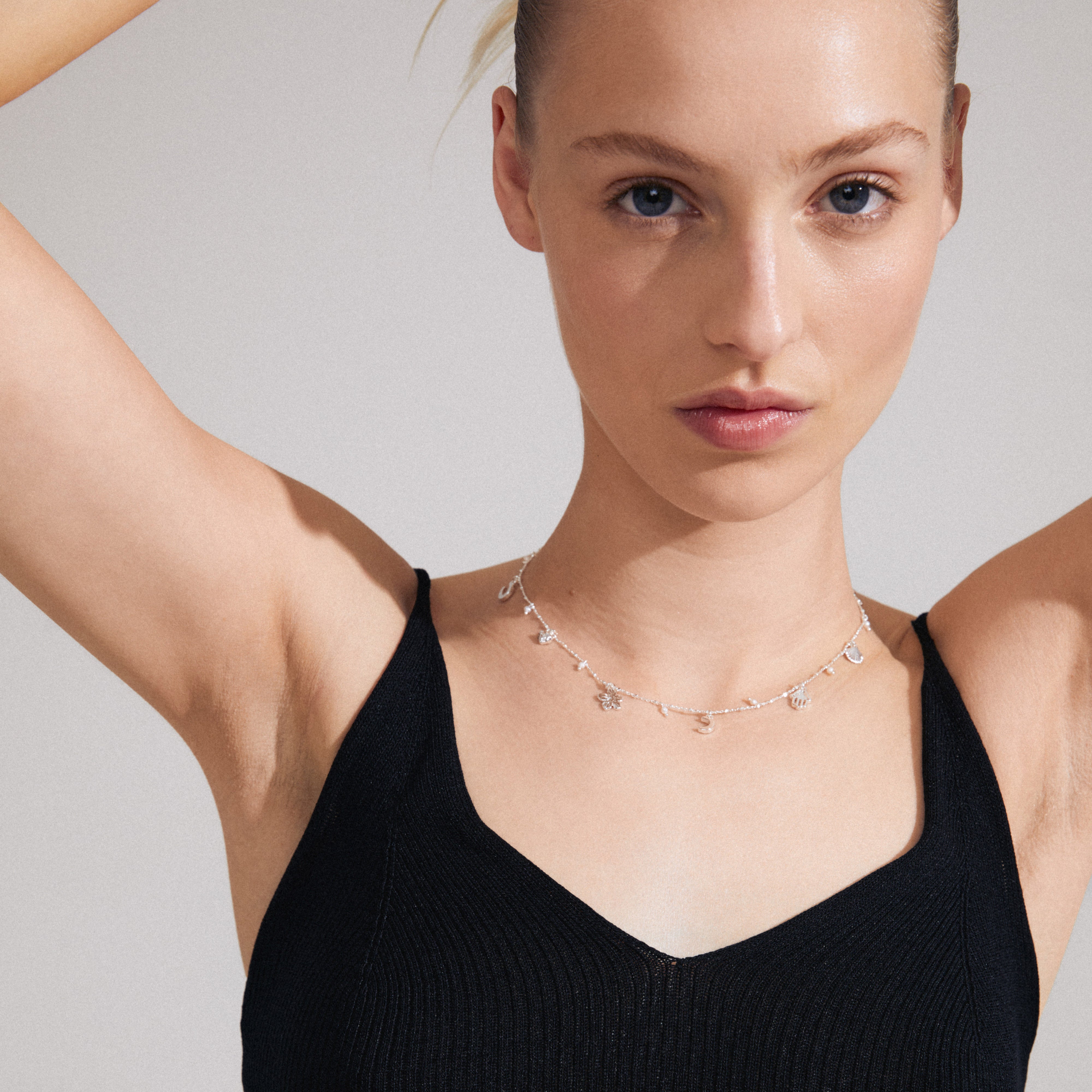 PRUCENCE necklace silver-plated with charms like a heart, moon, and Hamsa, worn by a woman, showcasing Pilgrim's blend of symbolism and elegance.