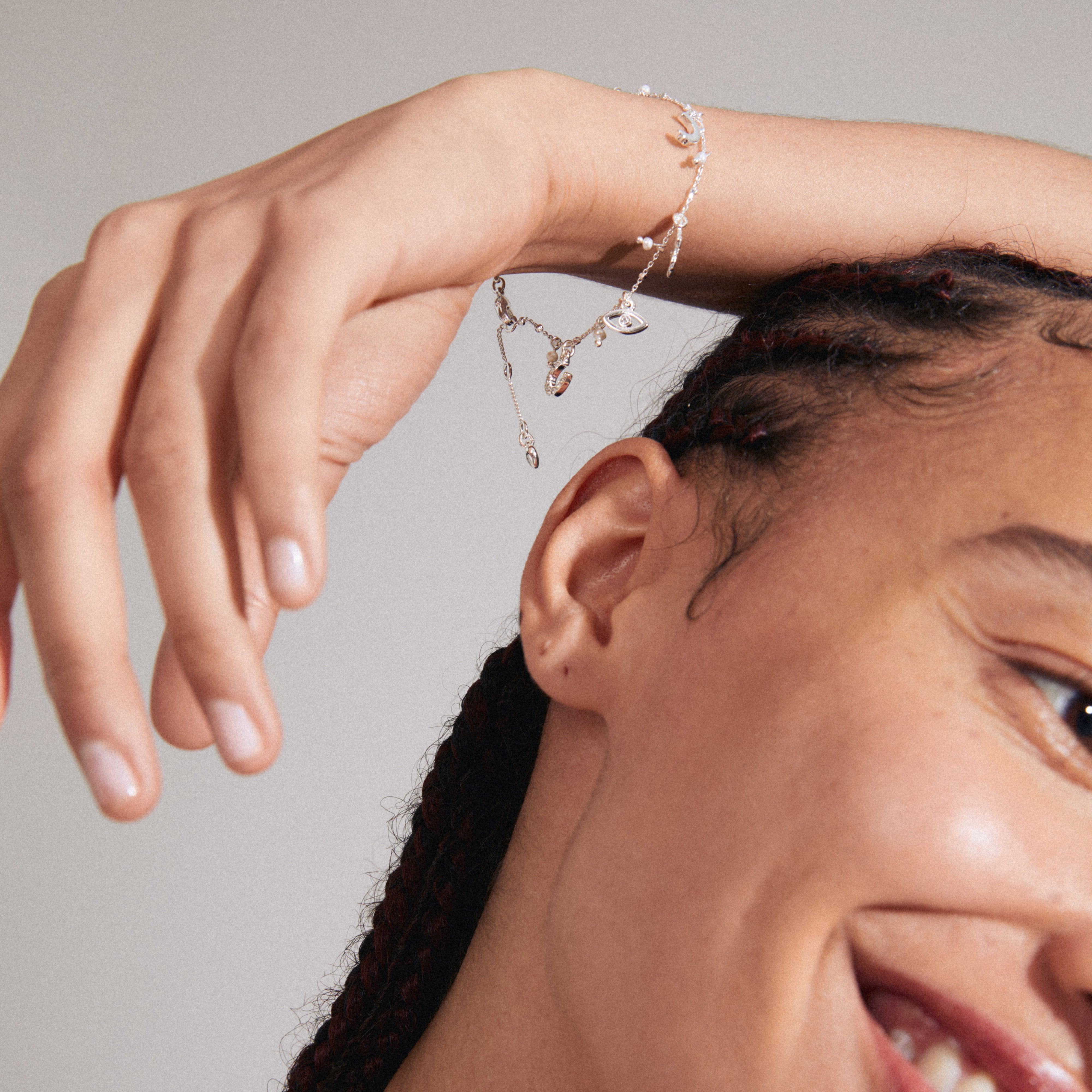 Close-up of a woman's wrist adorned with the silver-plated PRUCENCE bracelet, featuring various symbolic charms, including a heart, moon, and freshwater pearl.