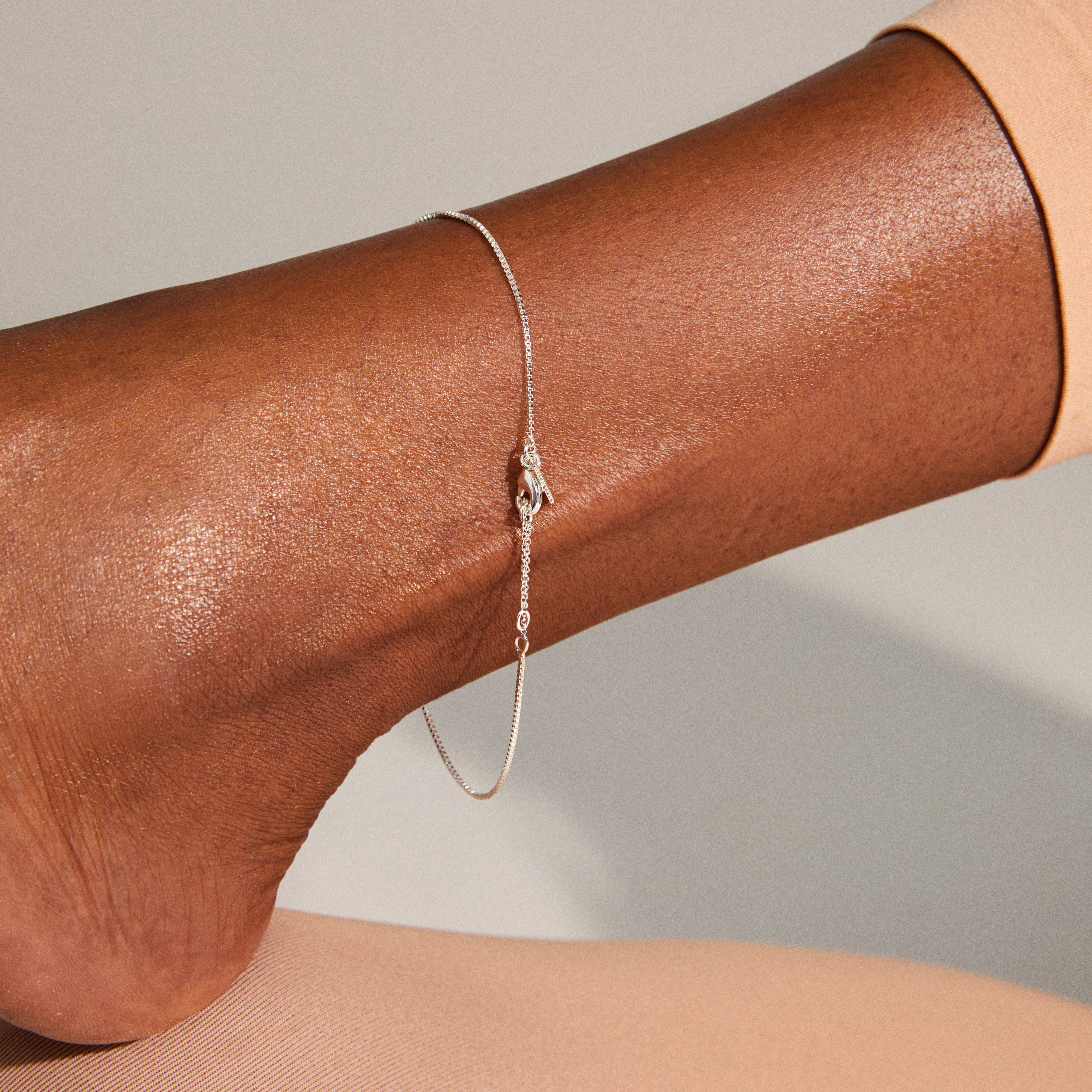 PALLAS anklet silver-plated elegantly draped on a person's ankle, showcasing its delicate chain detail. Perfect for enhancing personal style with a trendy, feminine touch.