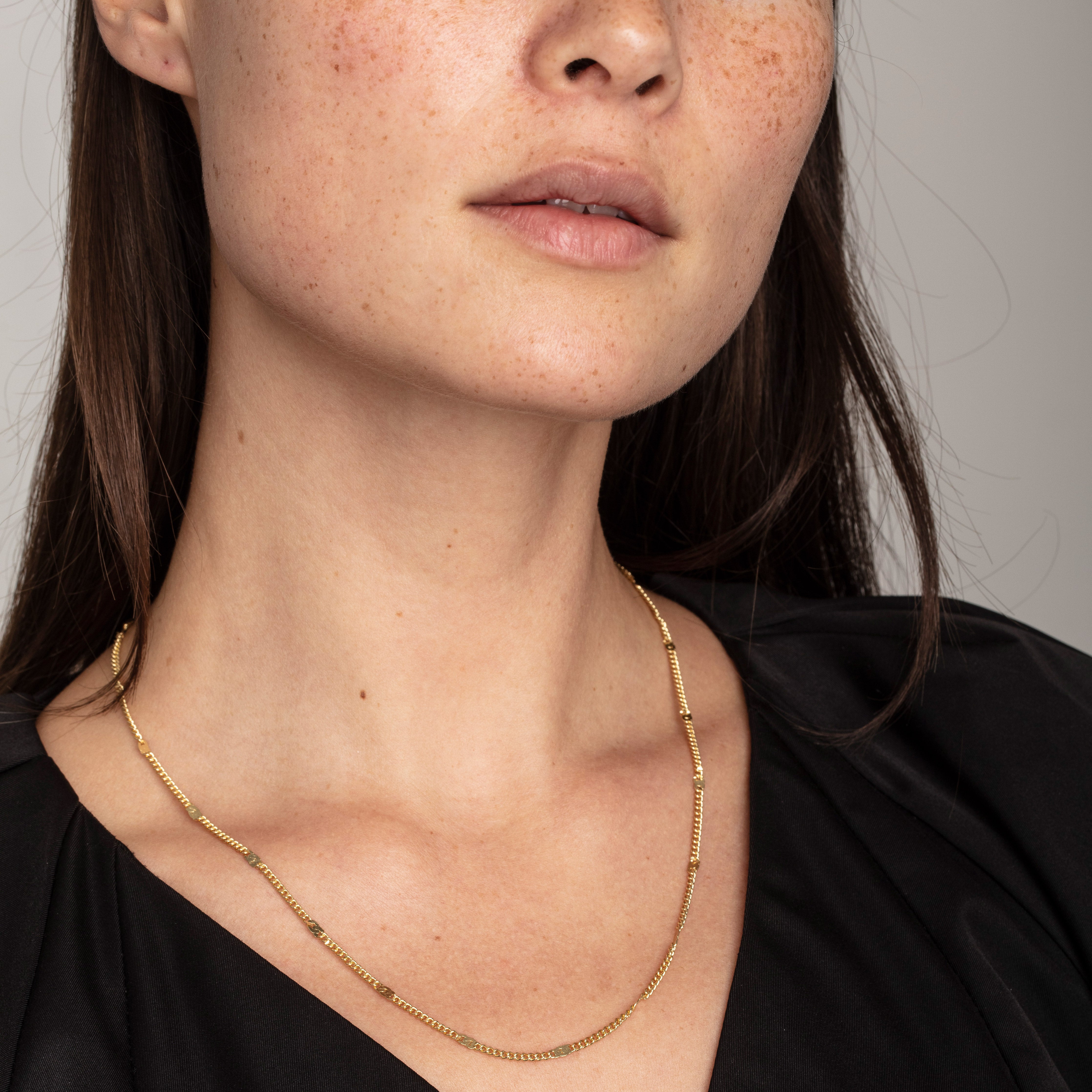Gold-plated CAT necklace with a textured, flattened-link design, worn by a woman, showcasing its 50 cm length with a 9 cm extension.