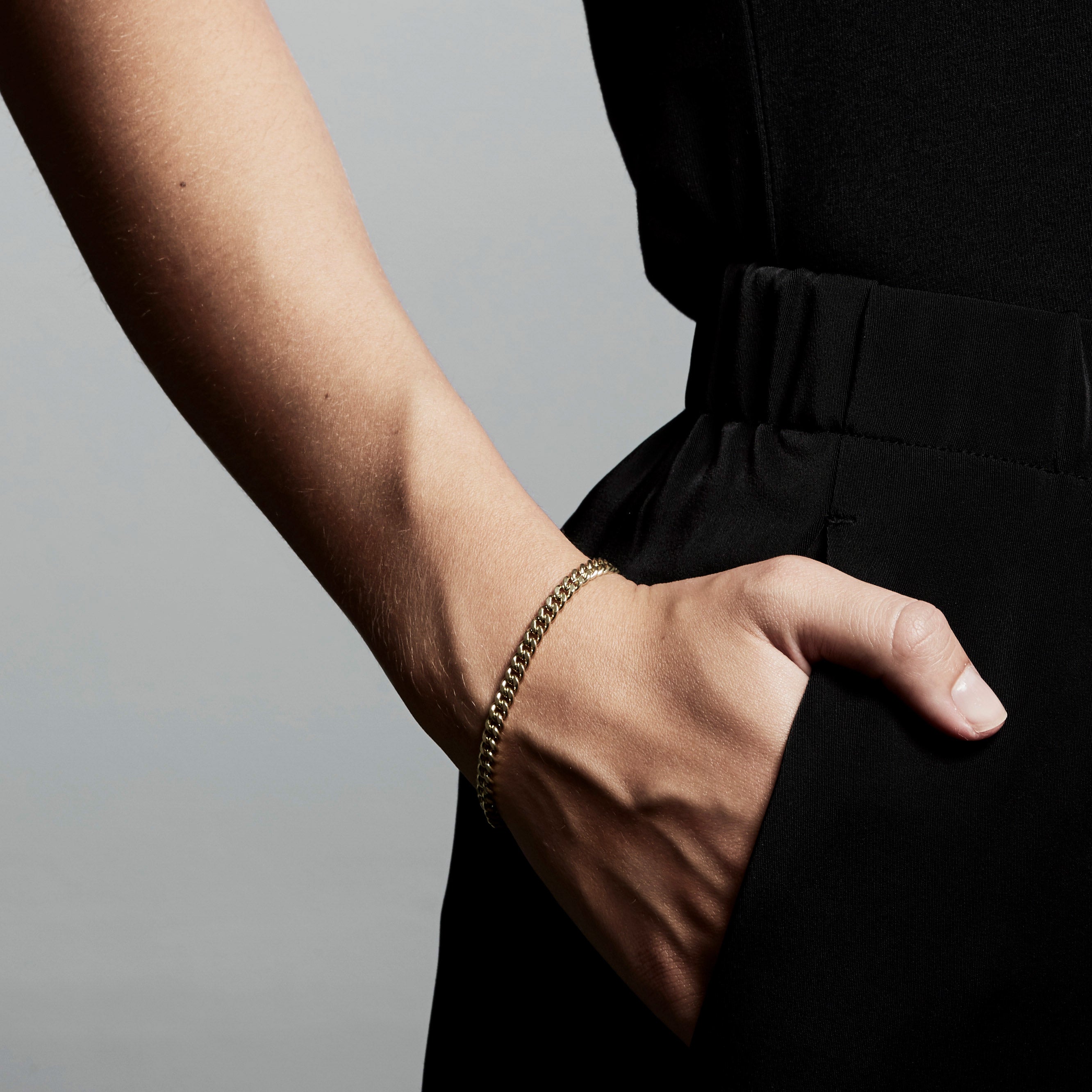 Gold-plated FUCHSIA curb chain bracelet on wrist, showcasing its semi-chunky, edgy, yet classic design, perfect for versatile and stylish fashion statements.