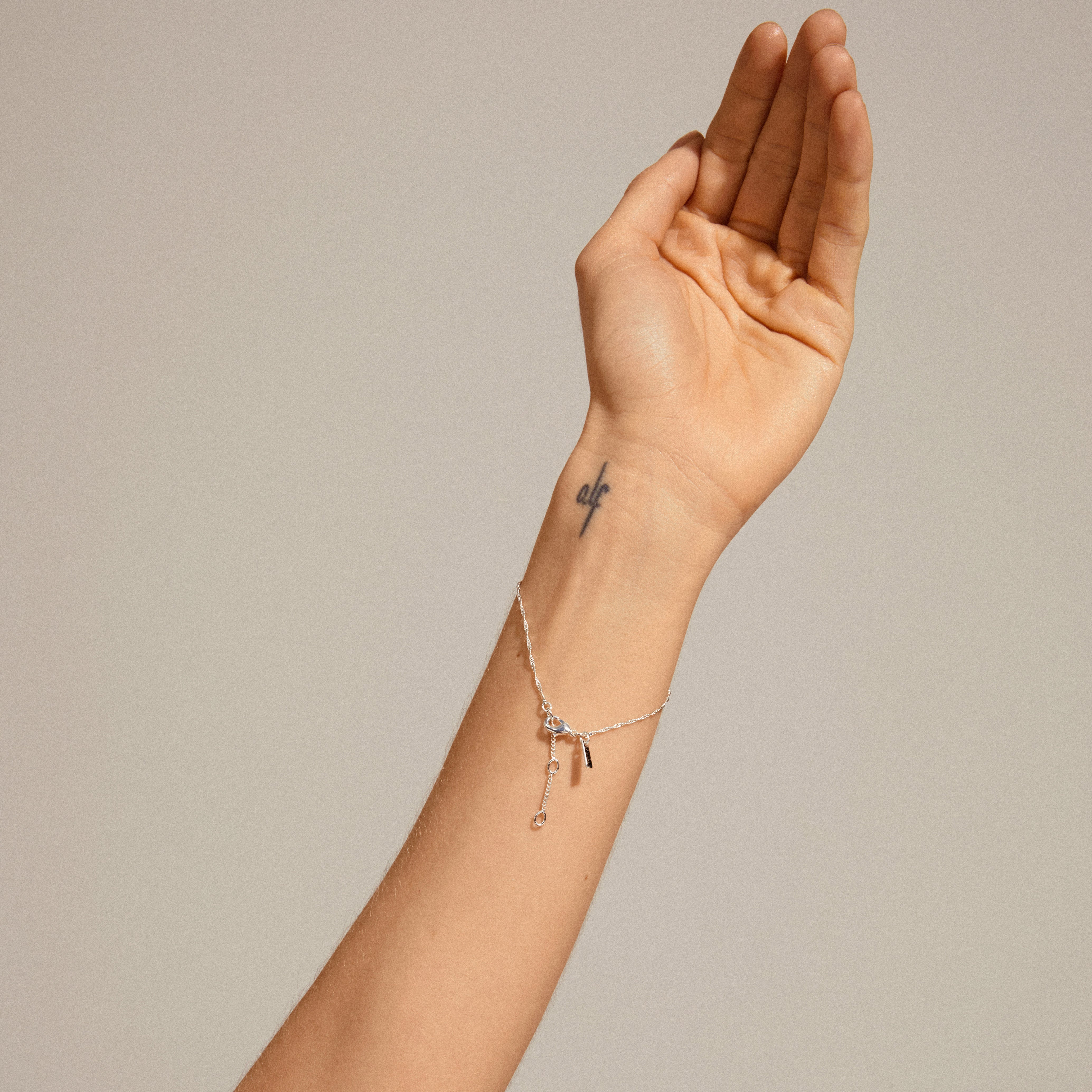 Silver-plated PERI twirl bracelet on tattooed wrist, showcasing its dense, detailed chain design. Perfect for everyday wear, embodying timeless elegance and Scandinavian craftsmanship.