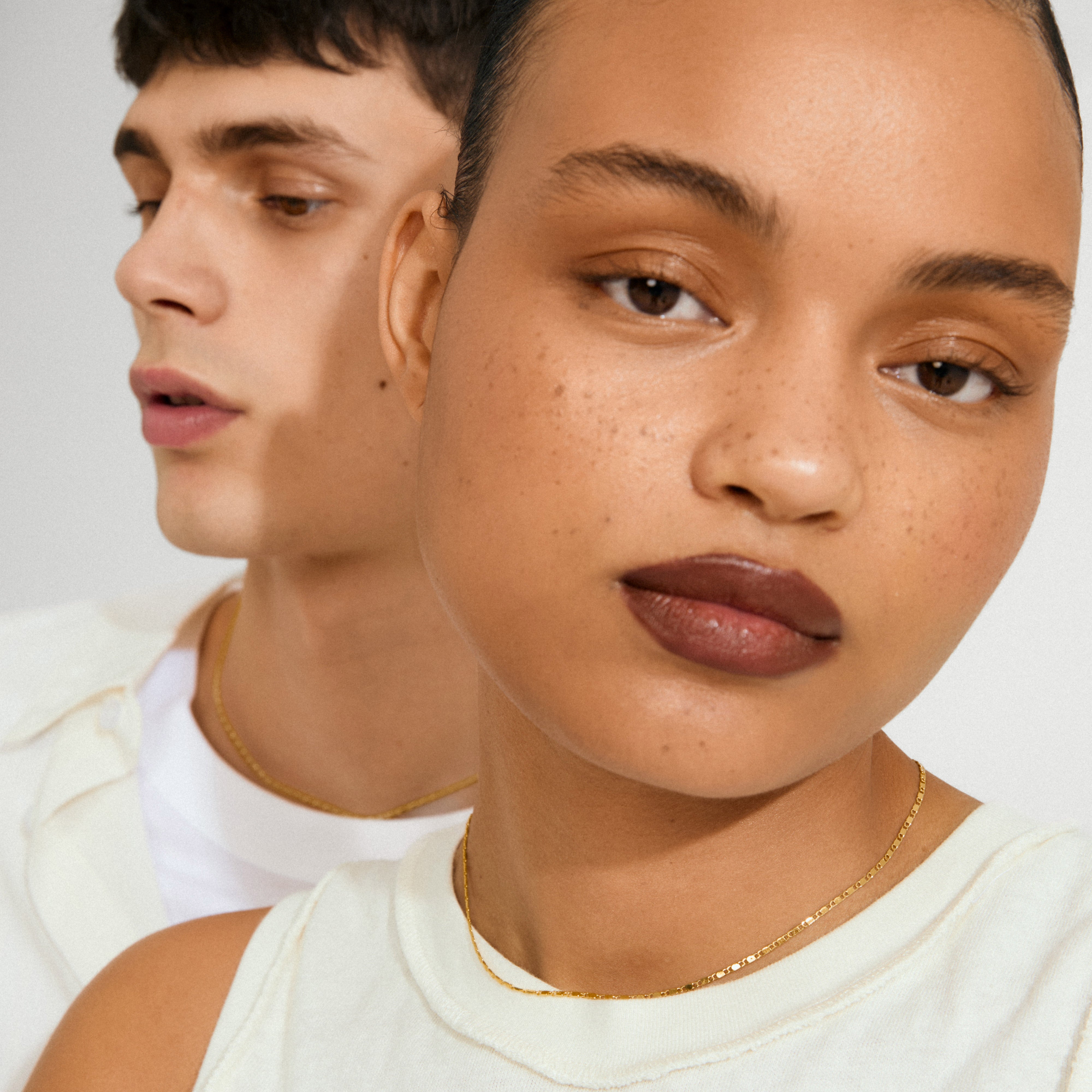 Close-up of two individuals wearing Pilgrim's PARISA flat link chain necklace, showcasing its gold-plated, polished links for a chic, layered look.